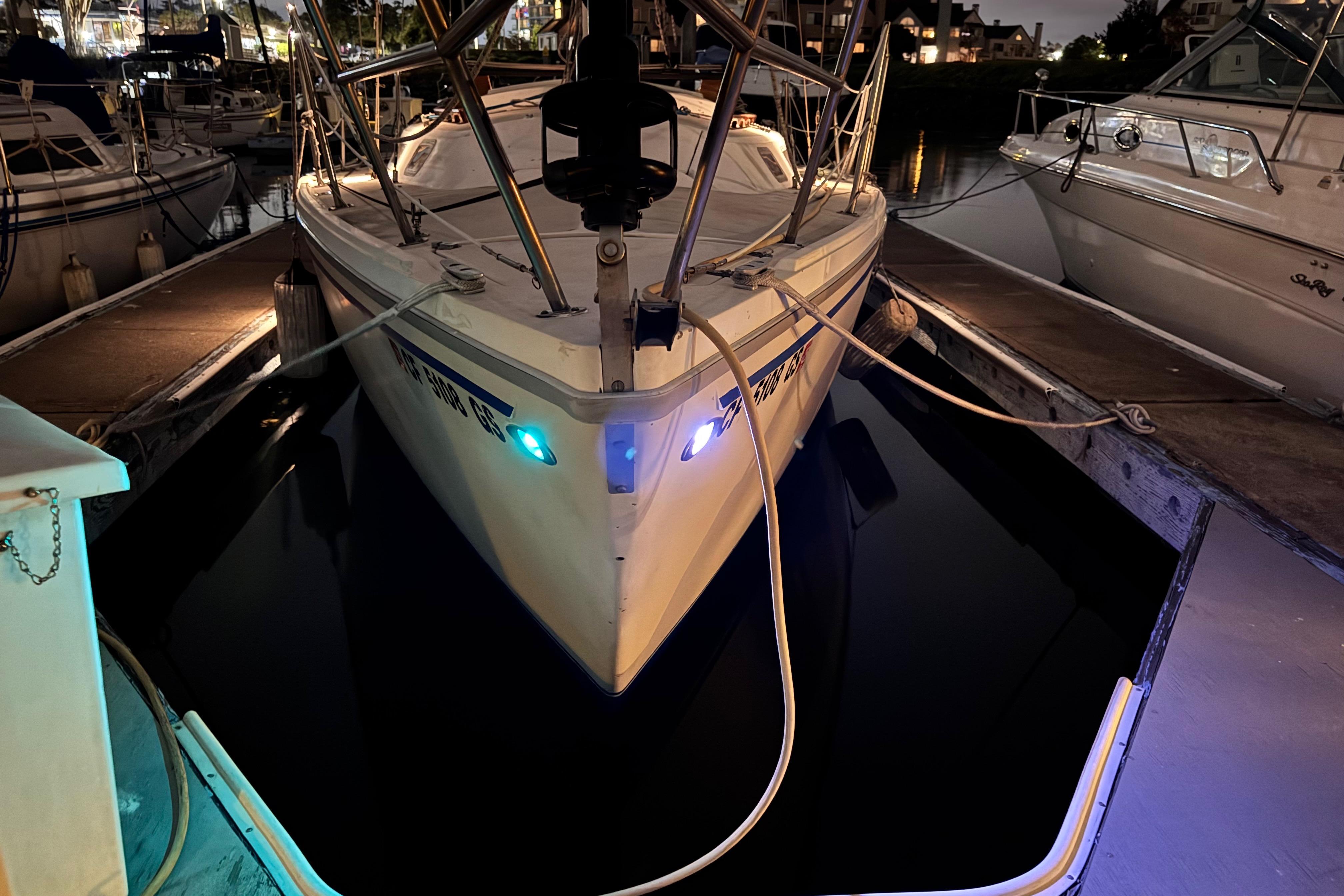 1980 Catalina 30 sailboat docked at night with illuminated navigation lights.