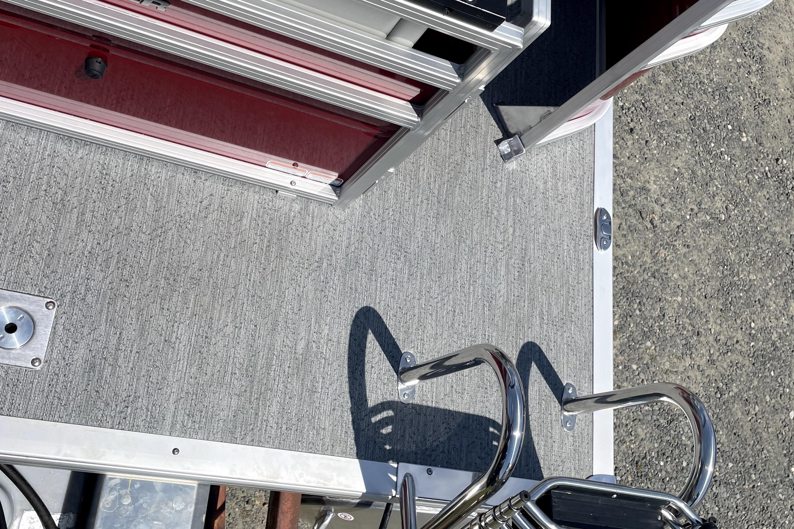 2026 Sun Tracker Fishin' Barge 22 DLX deck with ladder and storage compartment.