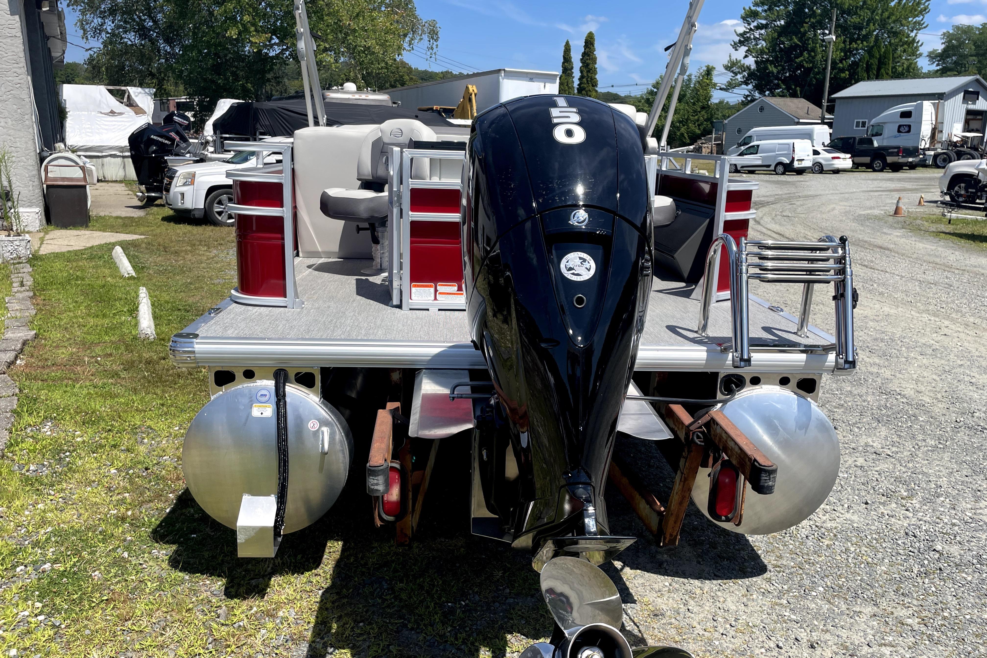 2026 Sun Tracker Fishin' Barge 22 DLX pontoon boat with outboard motor, parked outdoors.