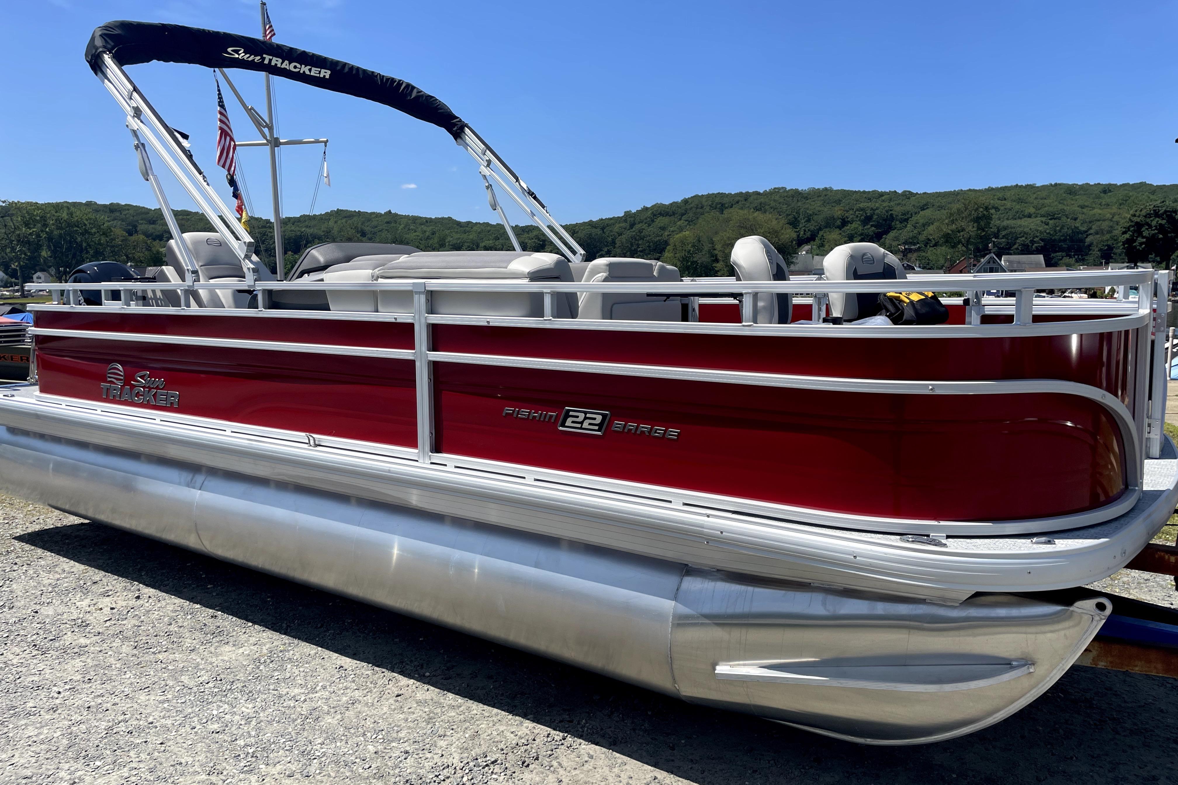 2026 Sun Tracker Fishin' Barge 22 DLX pontoon boat, red exterior, parked outdoors.