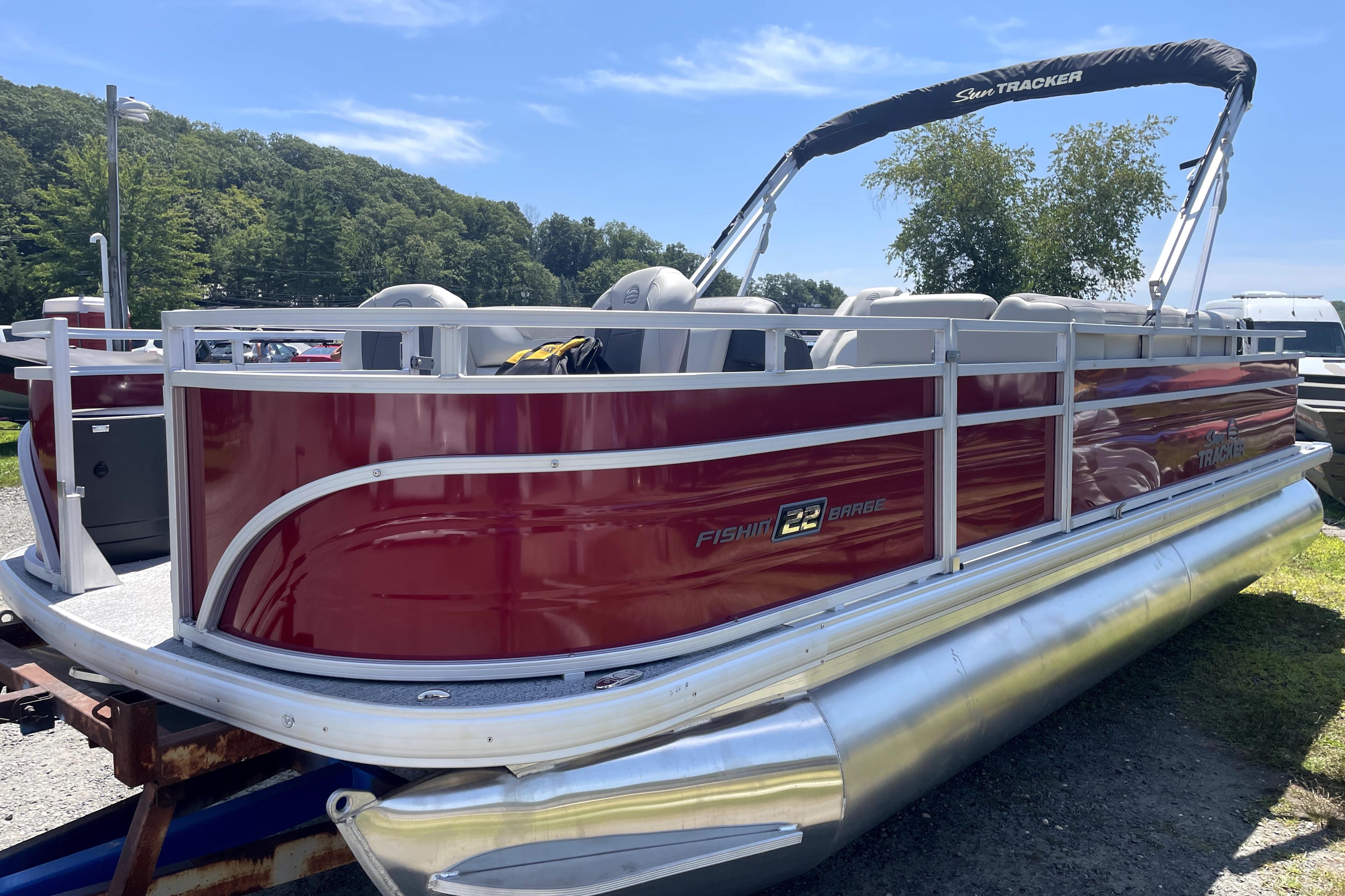 2026 Sun Tracker Fishin' Barge 22 DLX pontoon boat, red exterior, parked outdoors.