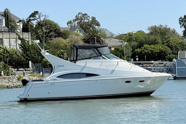1997 Carver 350 Mariner yacht on calm water, surrounded by lush greenery.