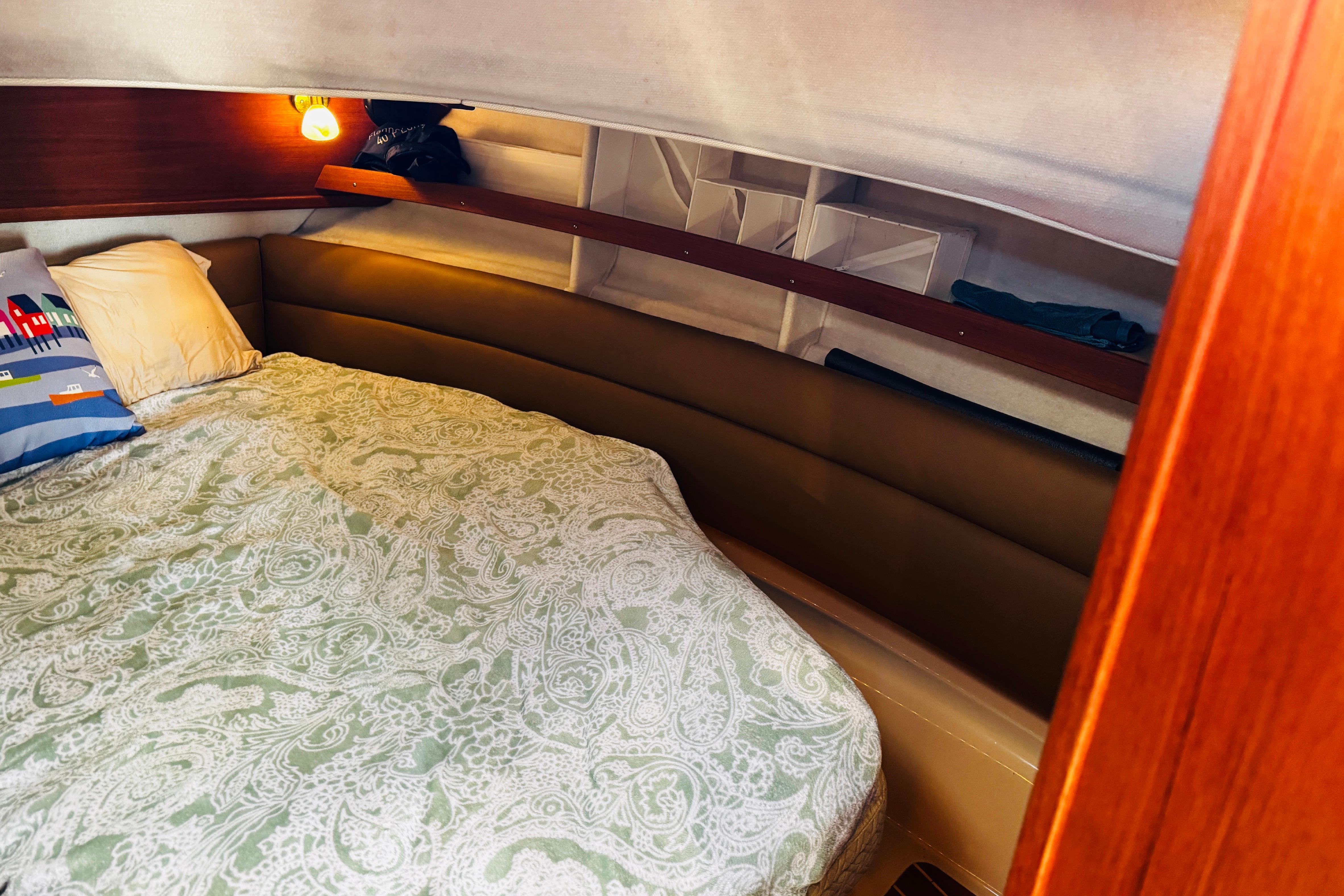 Cozy cabin interior of 2012 Ranger Tugs R-31 with patterned bedding and warm lighting.