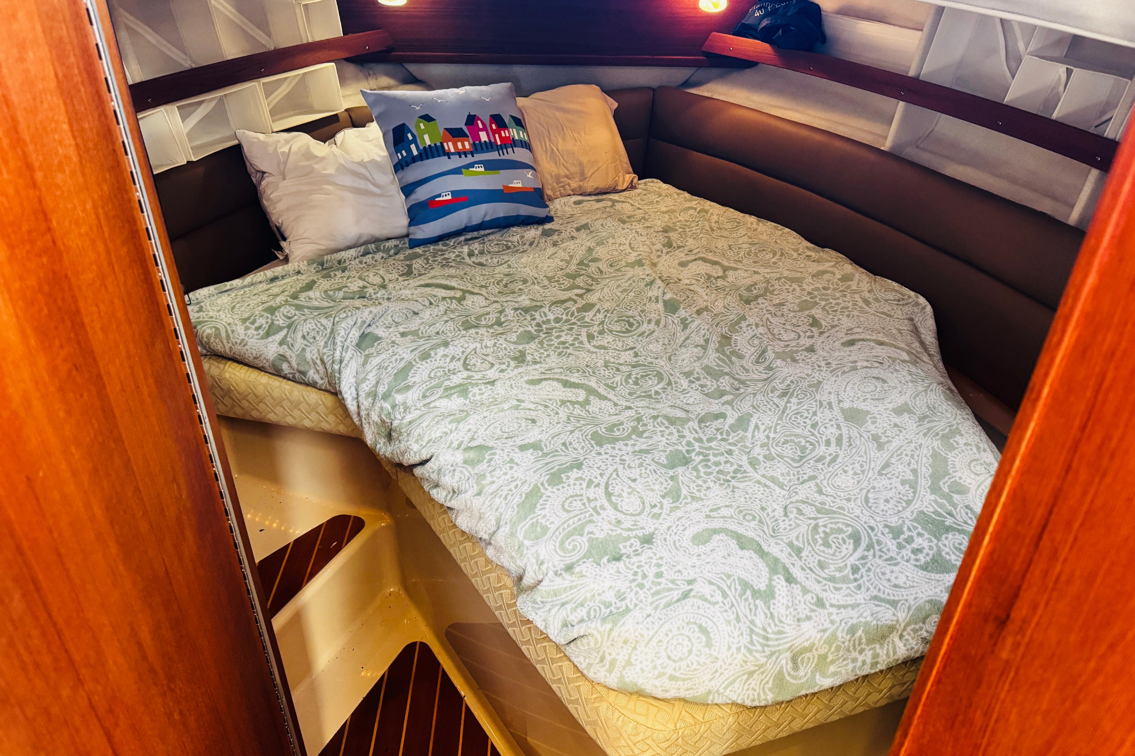 Cozy cabin interior of 2012 Ranger Tugs R-31 with a comfortable bed and decorative pillows.