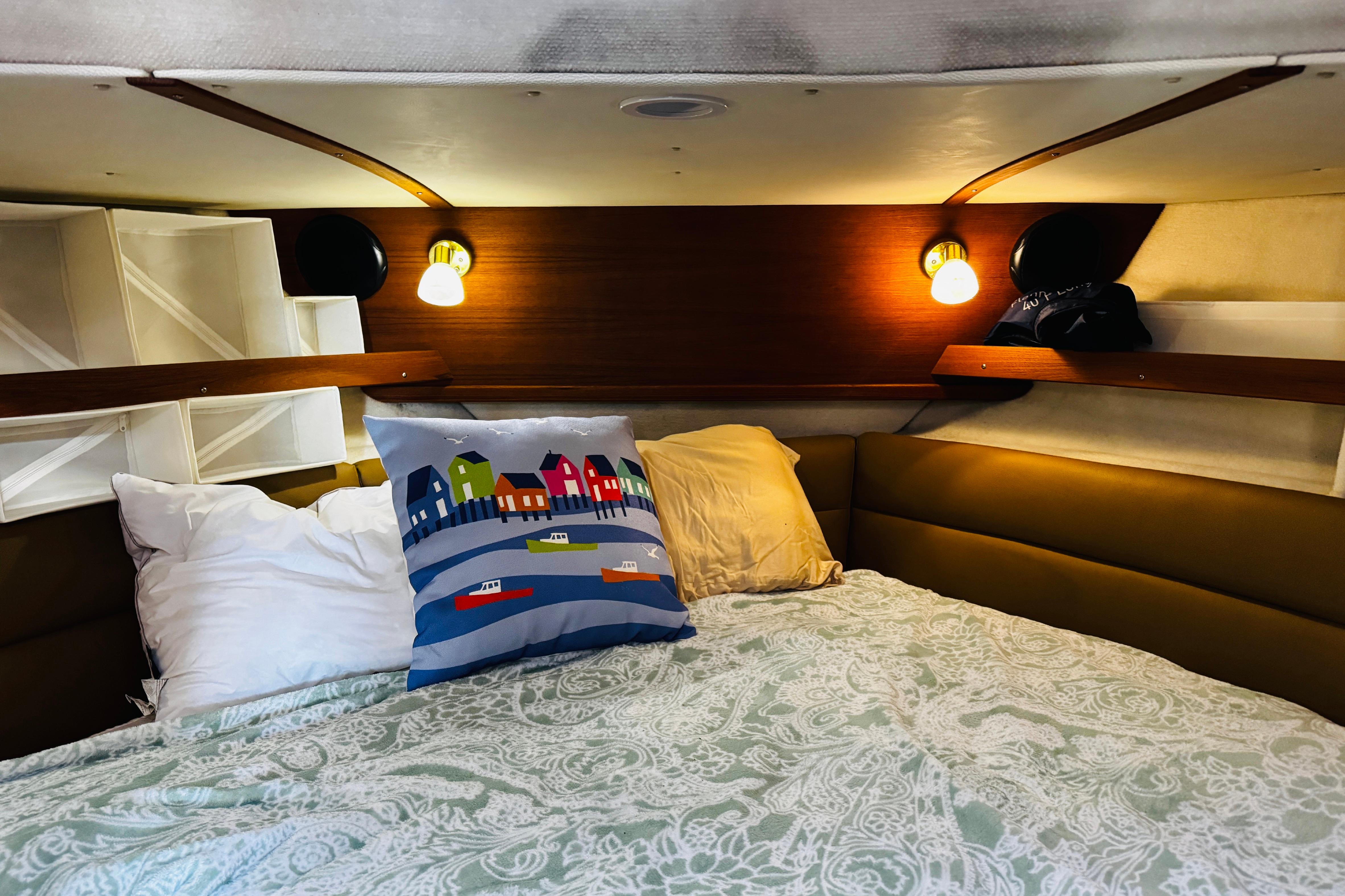 Cozy cabin interior of 2012 Ranger Tugs R-31 with decorative pillows and ambient lighting.