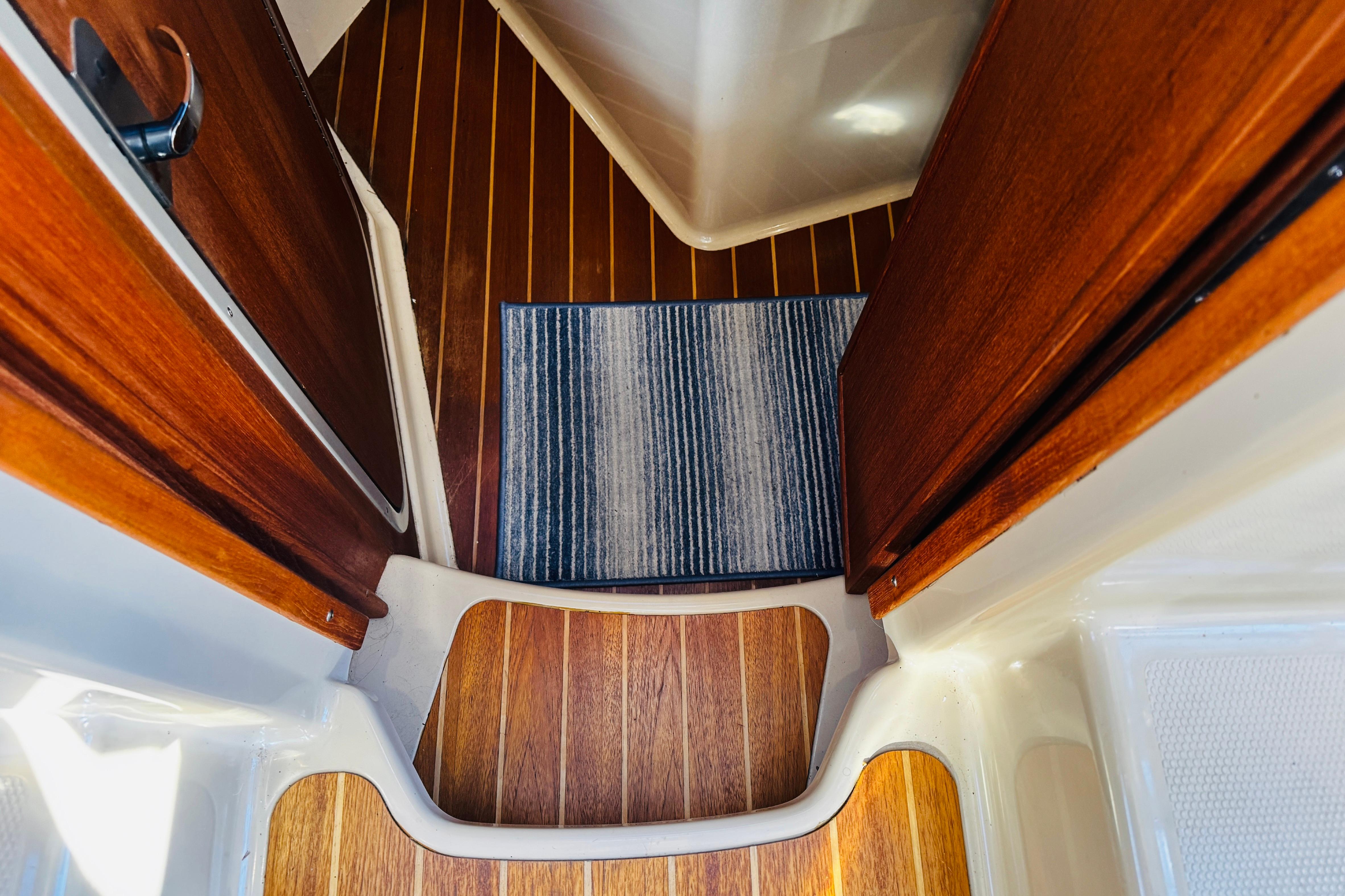 Interior view of 2012 Ranger Tugs R-31 with wooden flooring and striped rug.