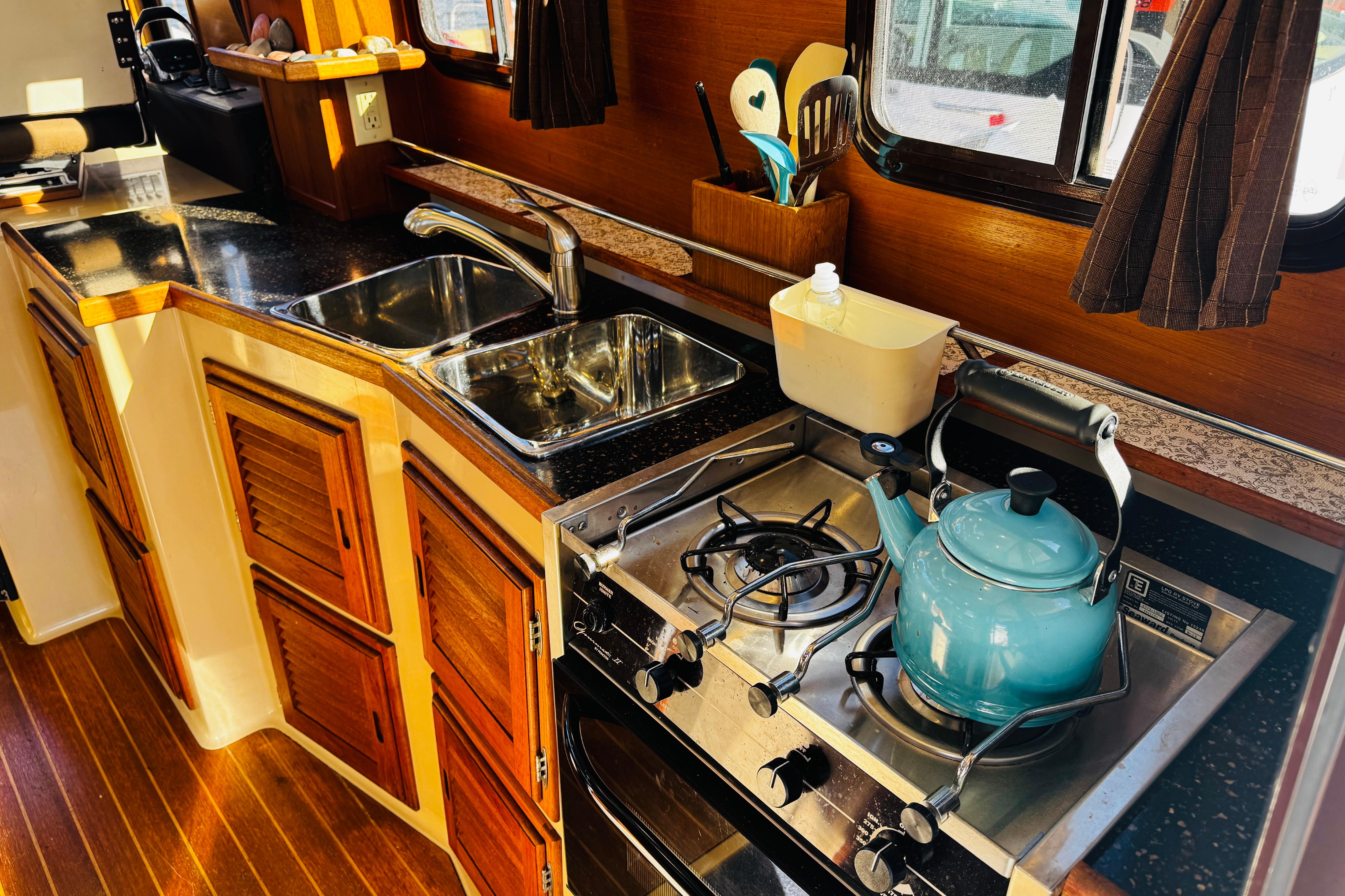 Cozy 2012 Ranger Tugs R-31 kitchen with stove, sink, and wooden cabinets.