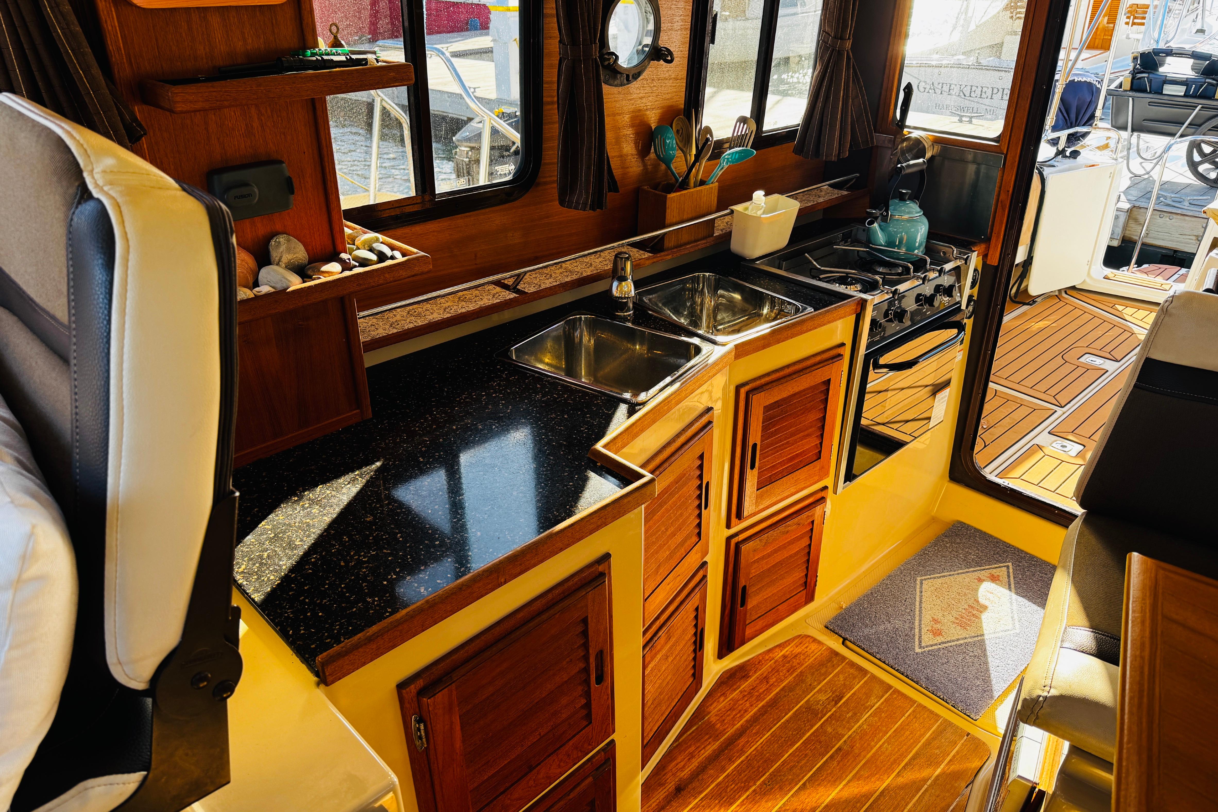 Interior of 2012 Ranger Tugs R-31 boat with wooden cabinetry and compact kitchen area.