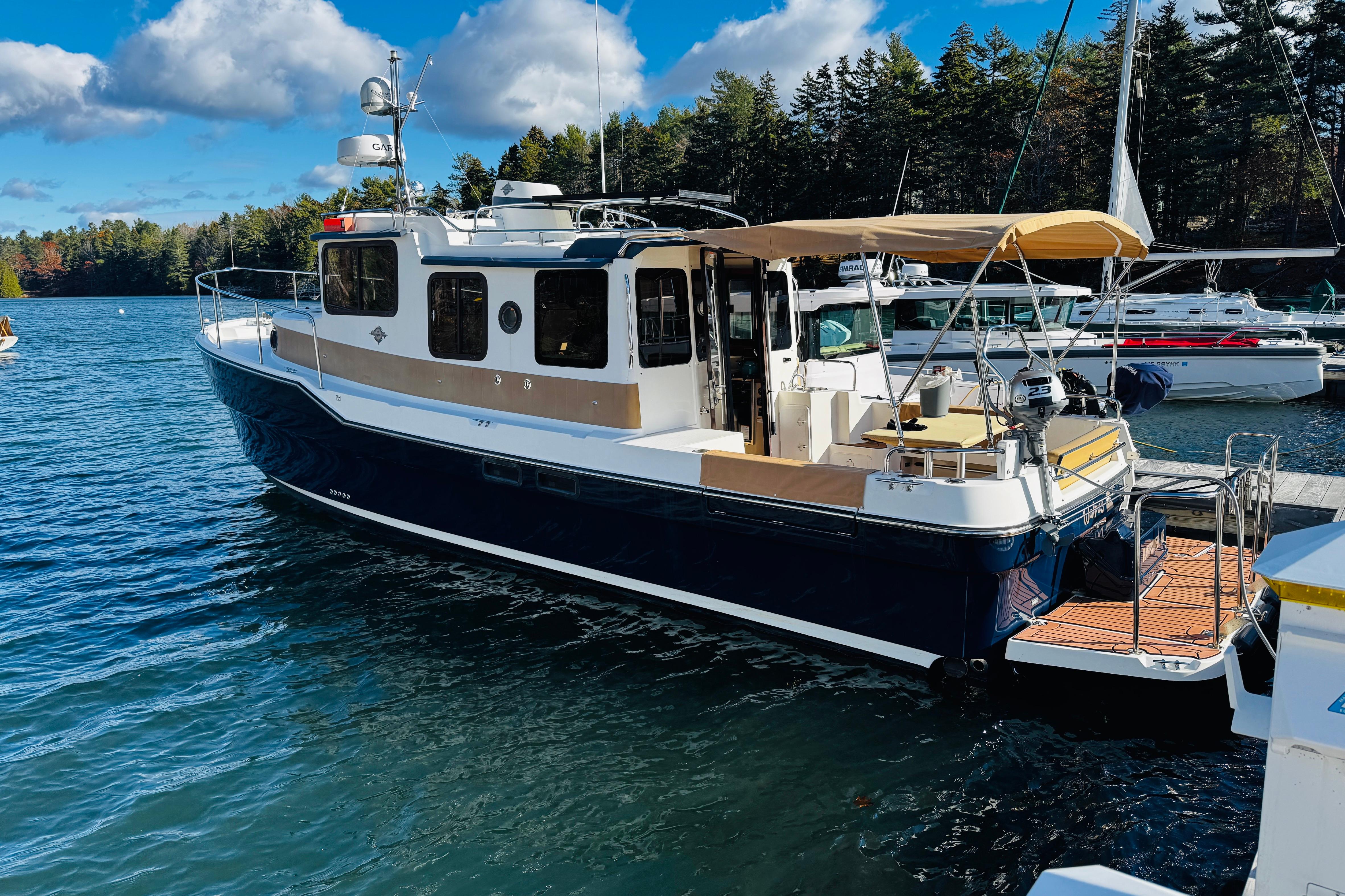 2012 Ranger Tugs R-31 boat docked on a sunny day with forest backdrop.