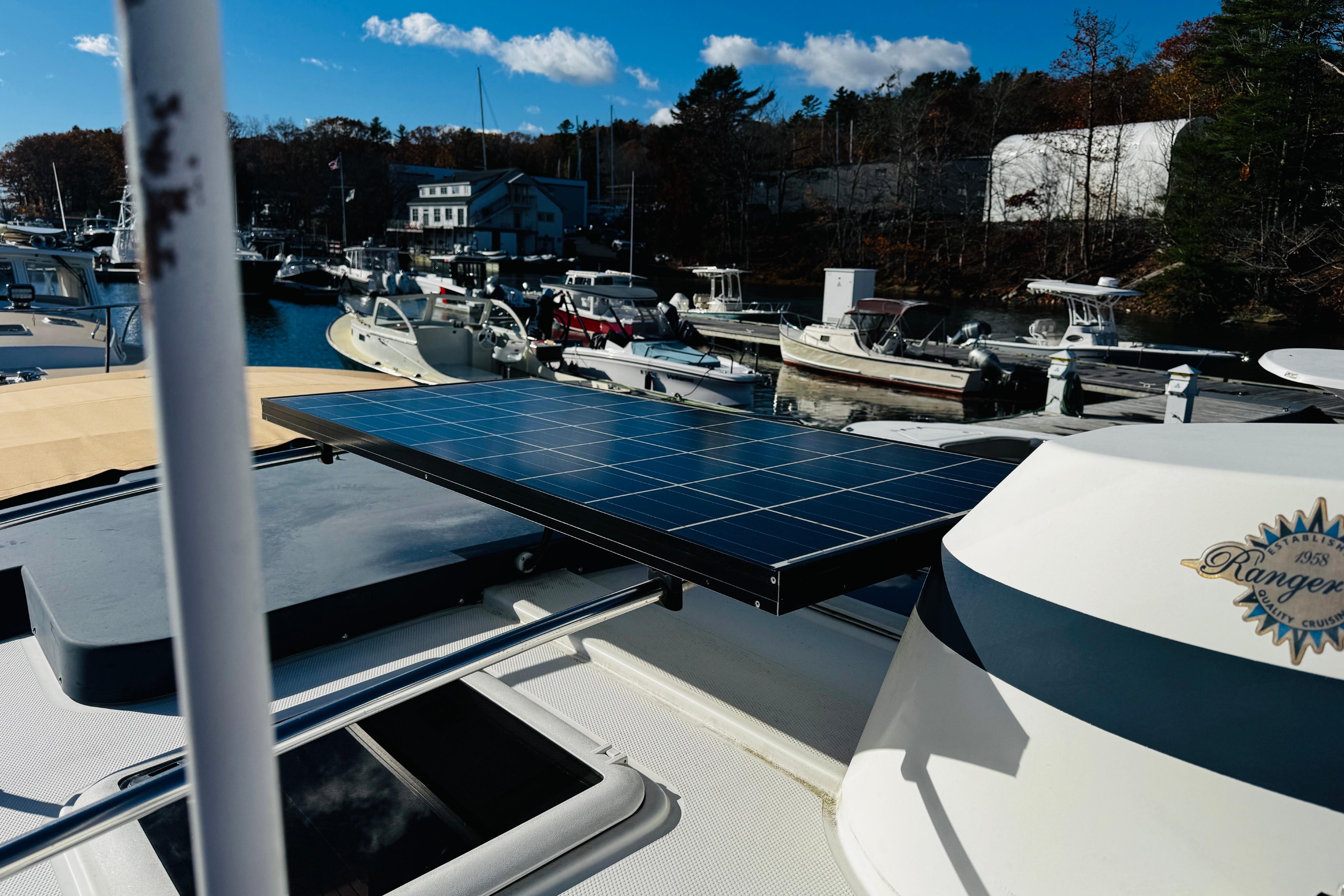 2012 Ranger Tugs R-31 with solar panel at marina, surrounded by boats and trees.