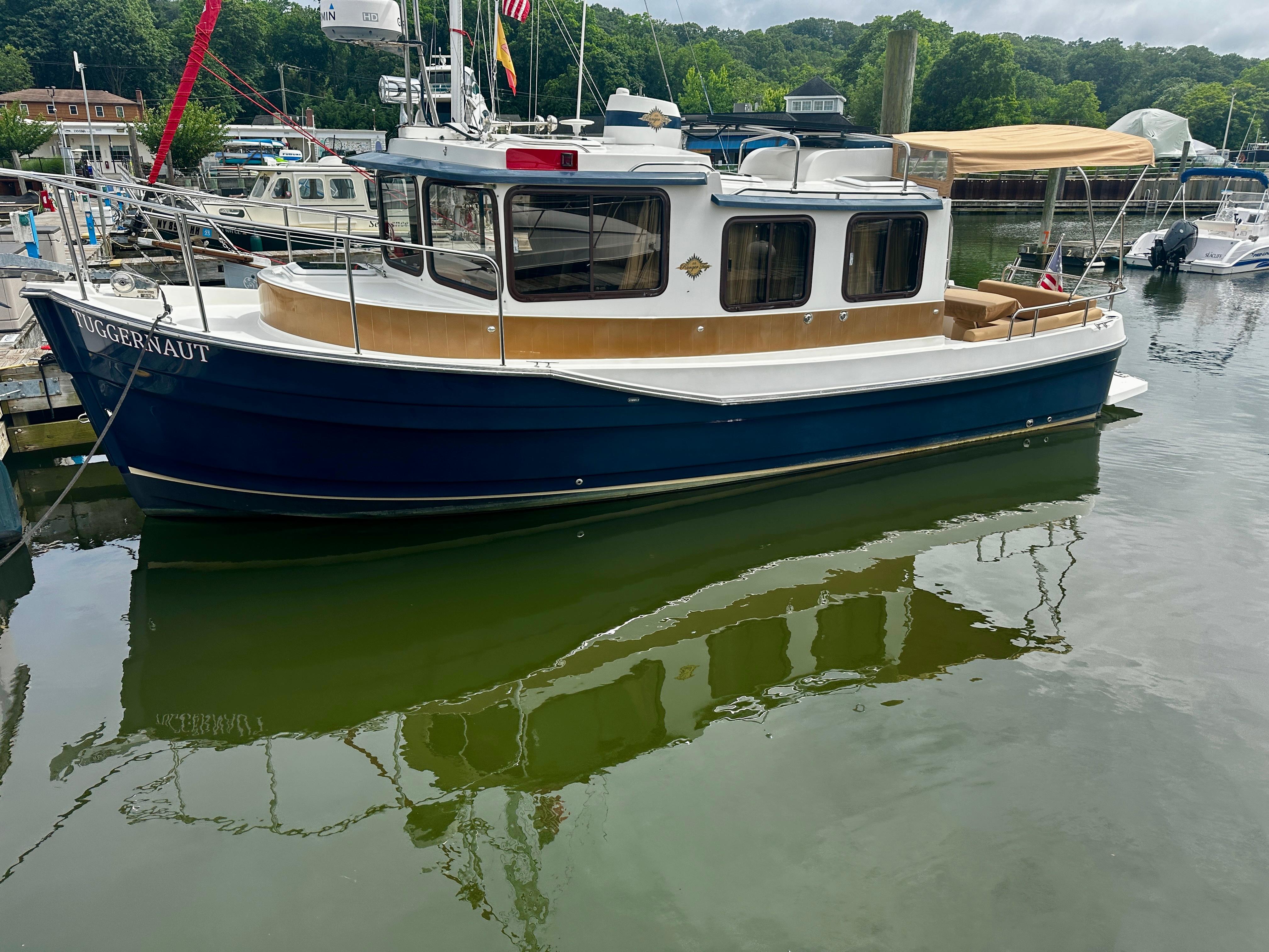 2014 American Tug R-27 boat docked in a marina, reflecting on calm water.