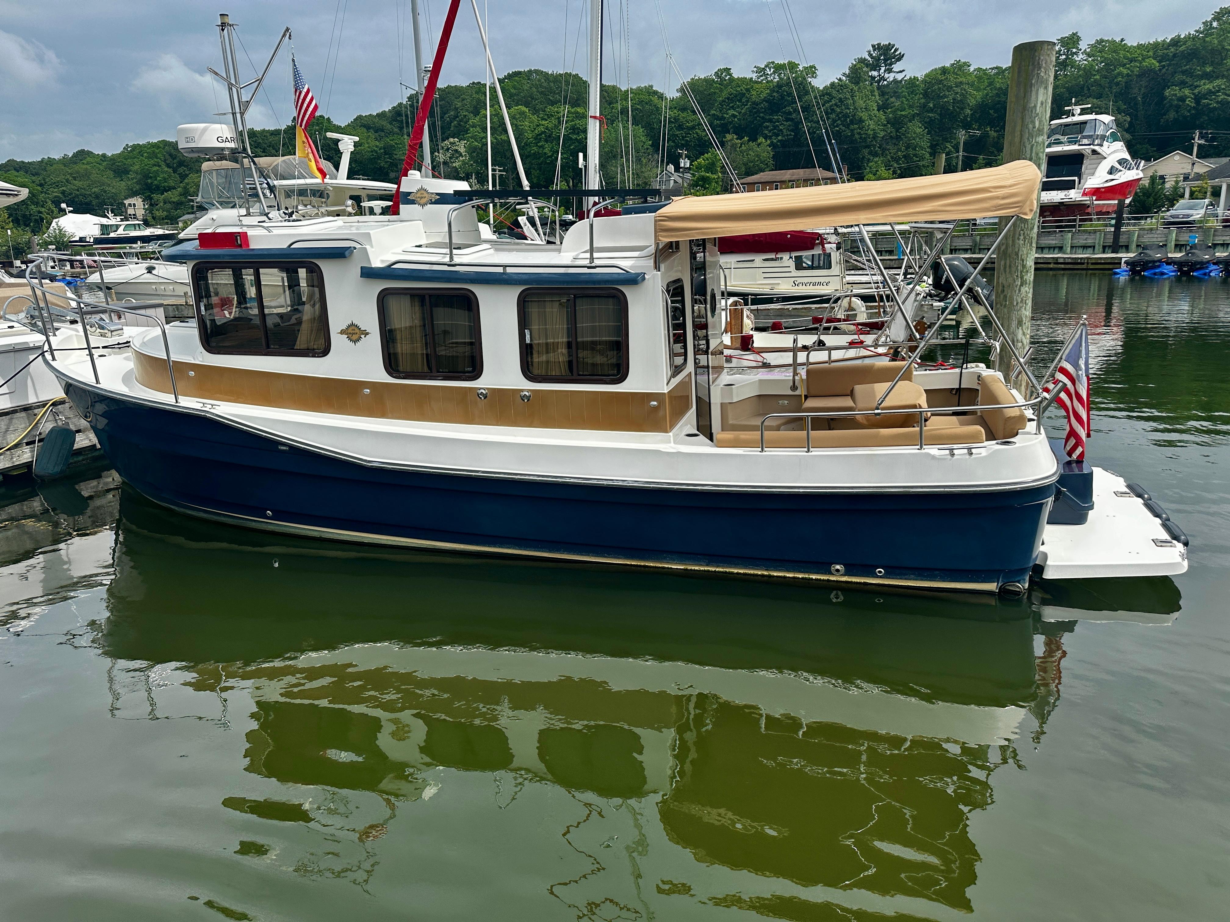2014 American Tug R-27 boat docked in a marina, featuring a blue hull and beige canopy.