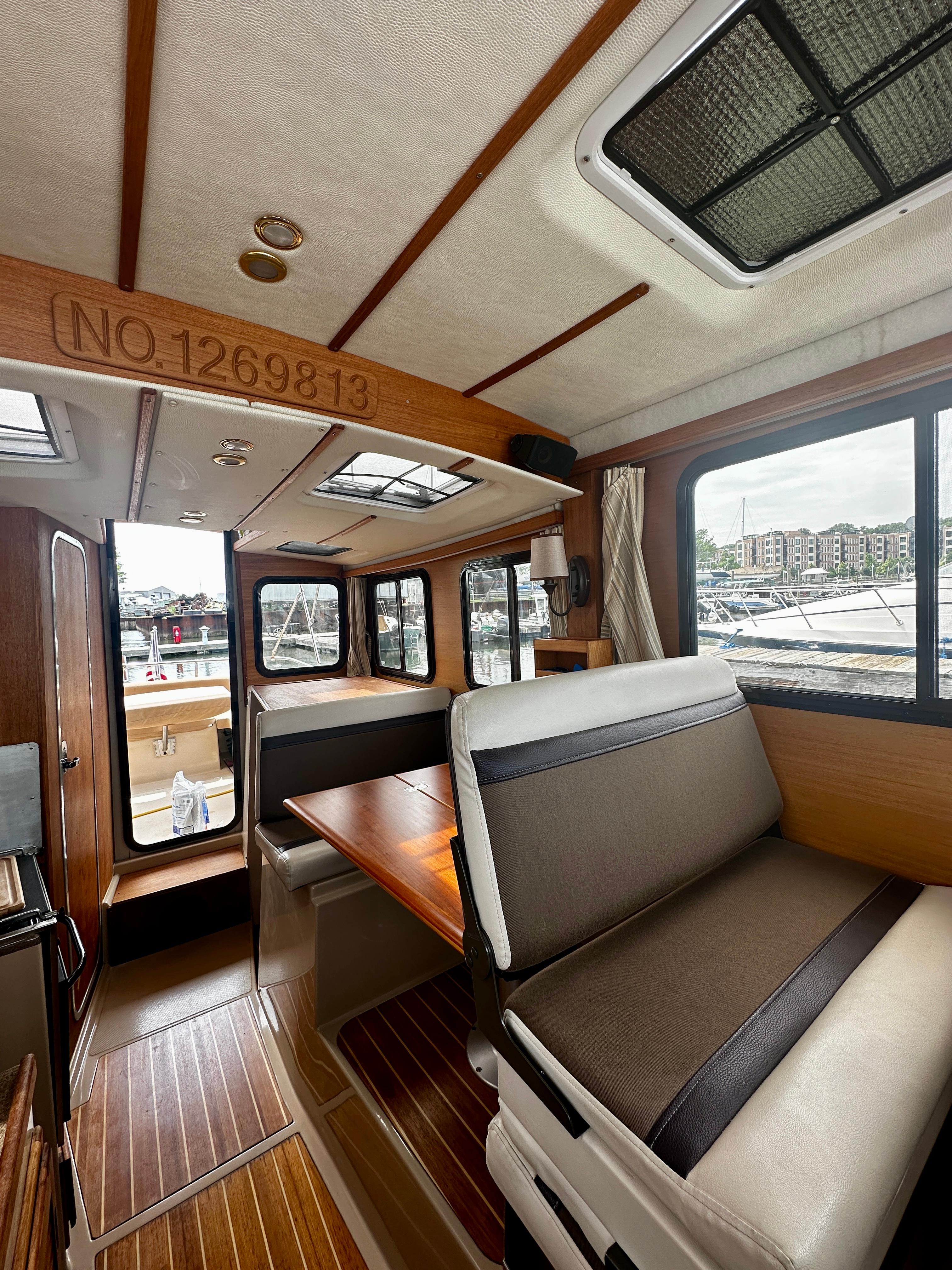 2014 American Tug R-27 interior with wood accents and seating, dock view outside.