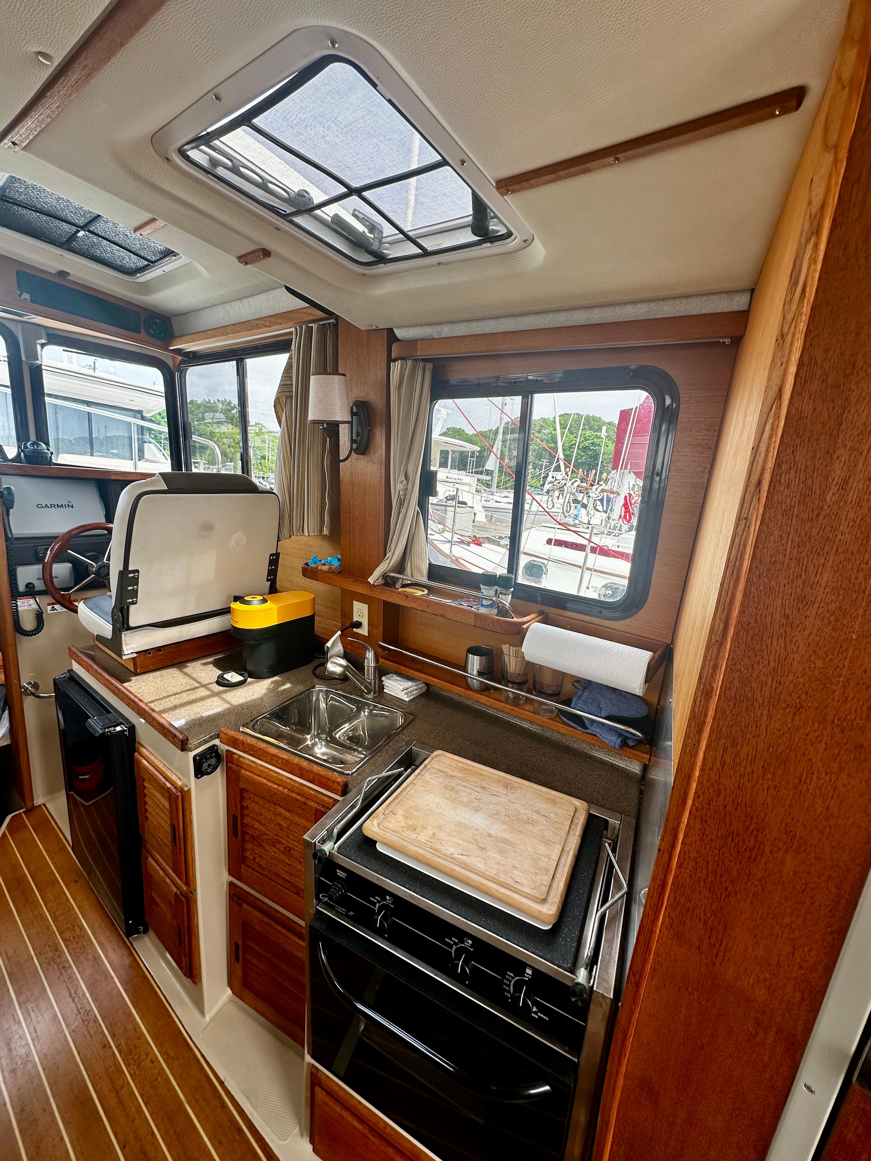 Interior of 2014 American Tug R-27, featuring a compact kitchen with stove and sink.