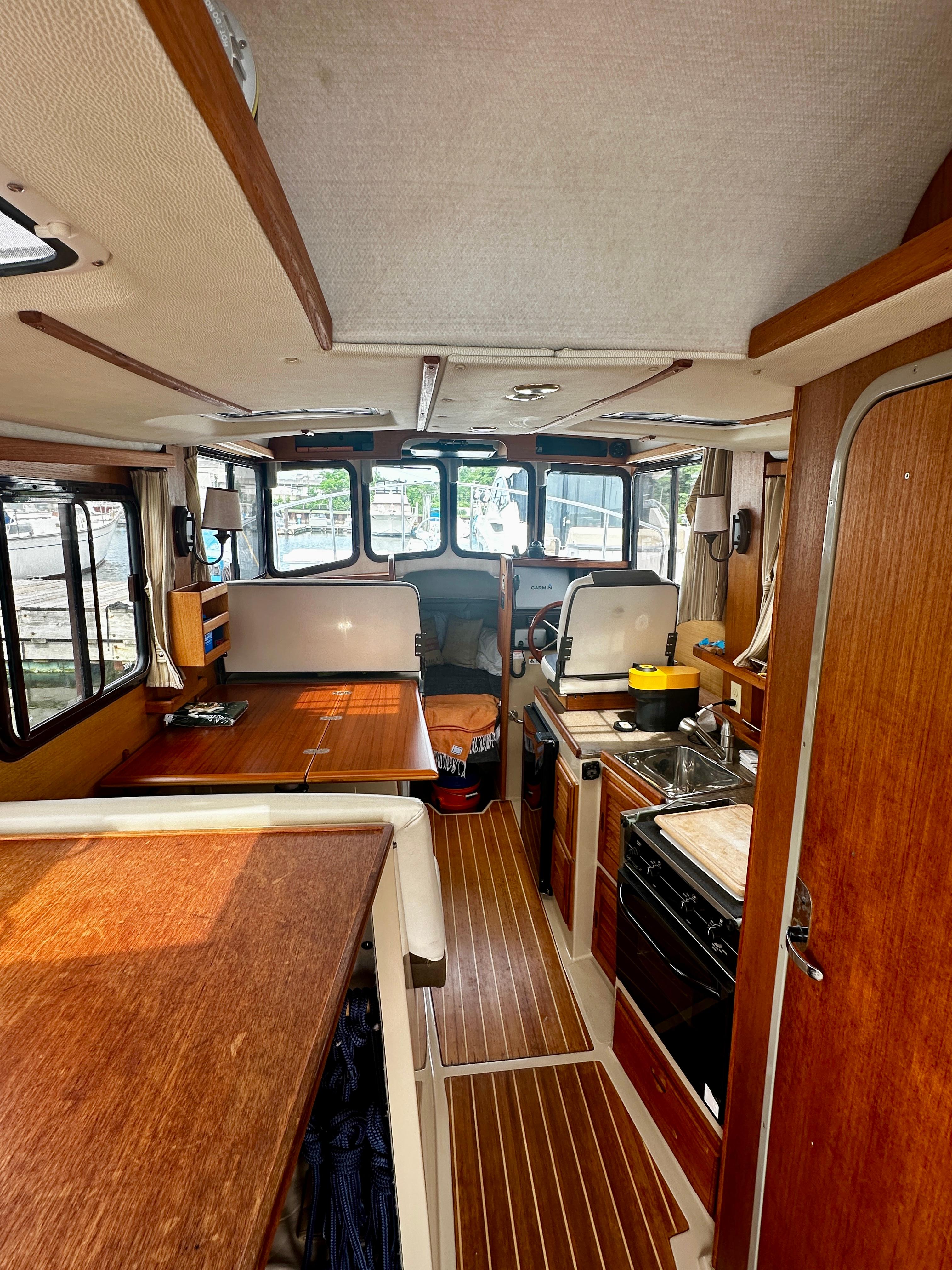 Interior of 2014 American Tug R-27, featuring wood finishes and compact kitchen area.