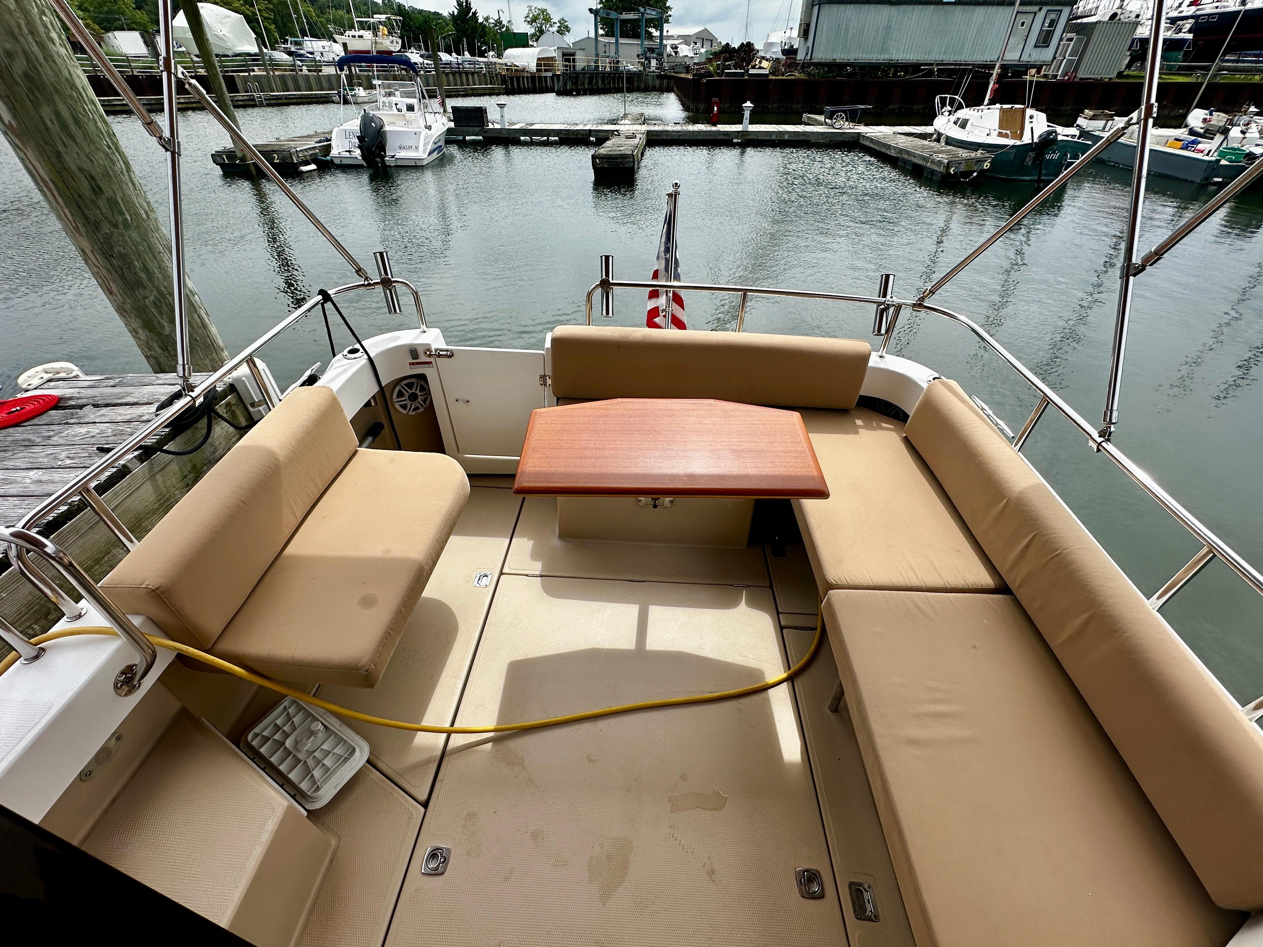 2014 American Tug R-27 boat deck with seating and table, docked at marina.