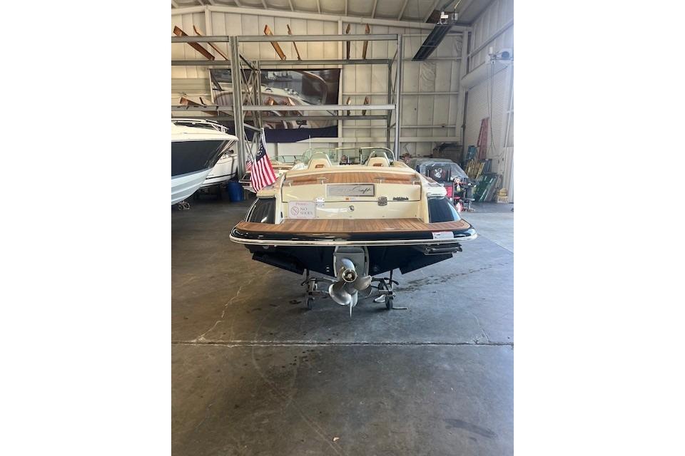 2024 Chris-Craft Launch 27 boat in a warehouse, rear view with American flag.