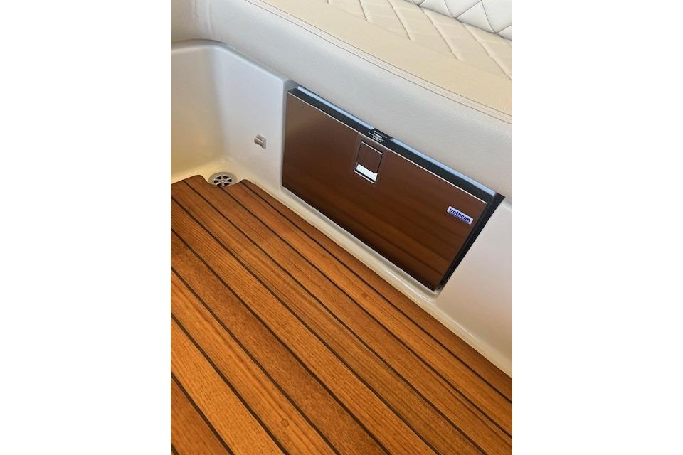 2024 Chris-Craft Launch 27 interior with teak flooring and built-in cooler.