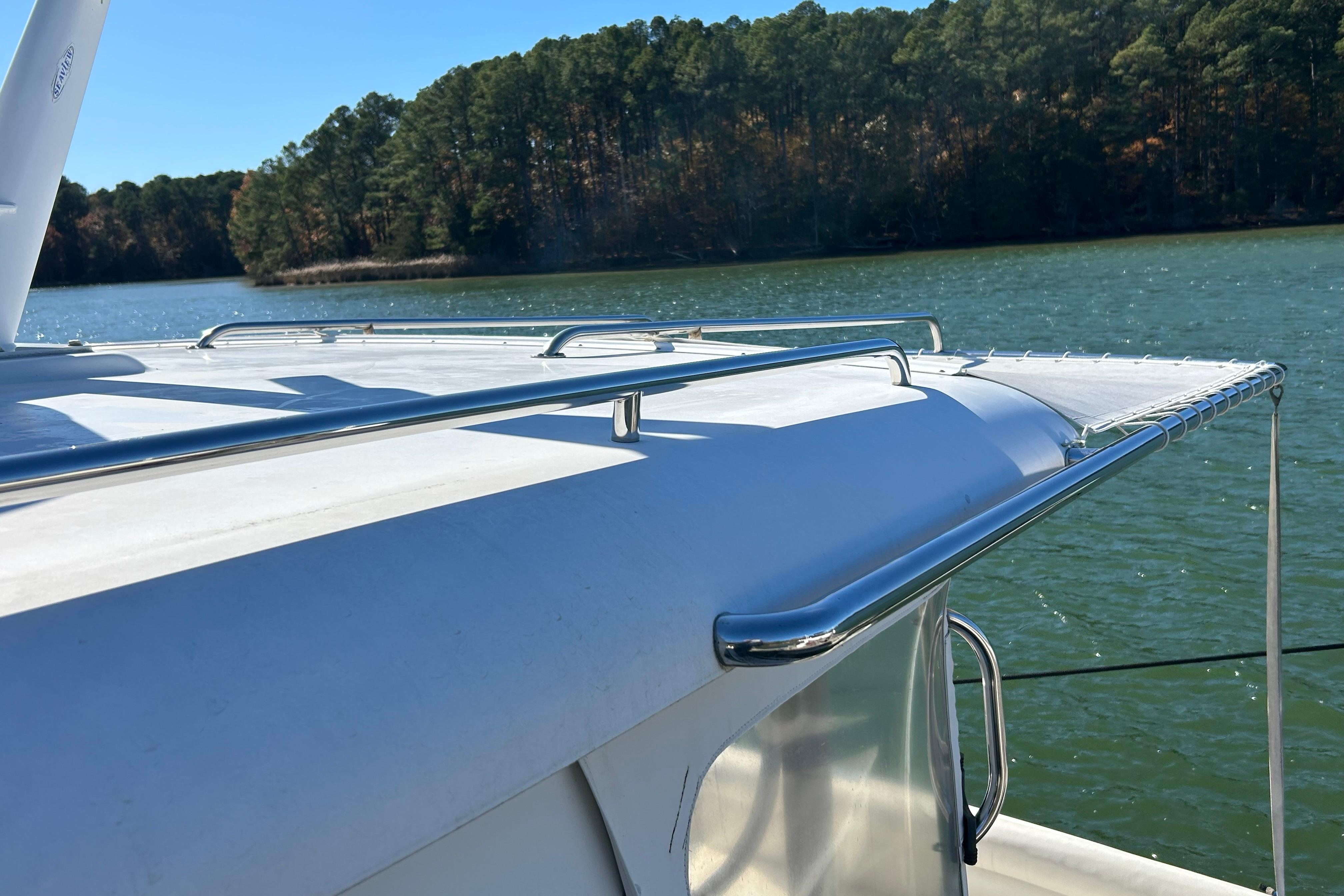 2008 Back Cove 33 boat roof with railing, overlooking serene lake and forest.