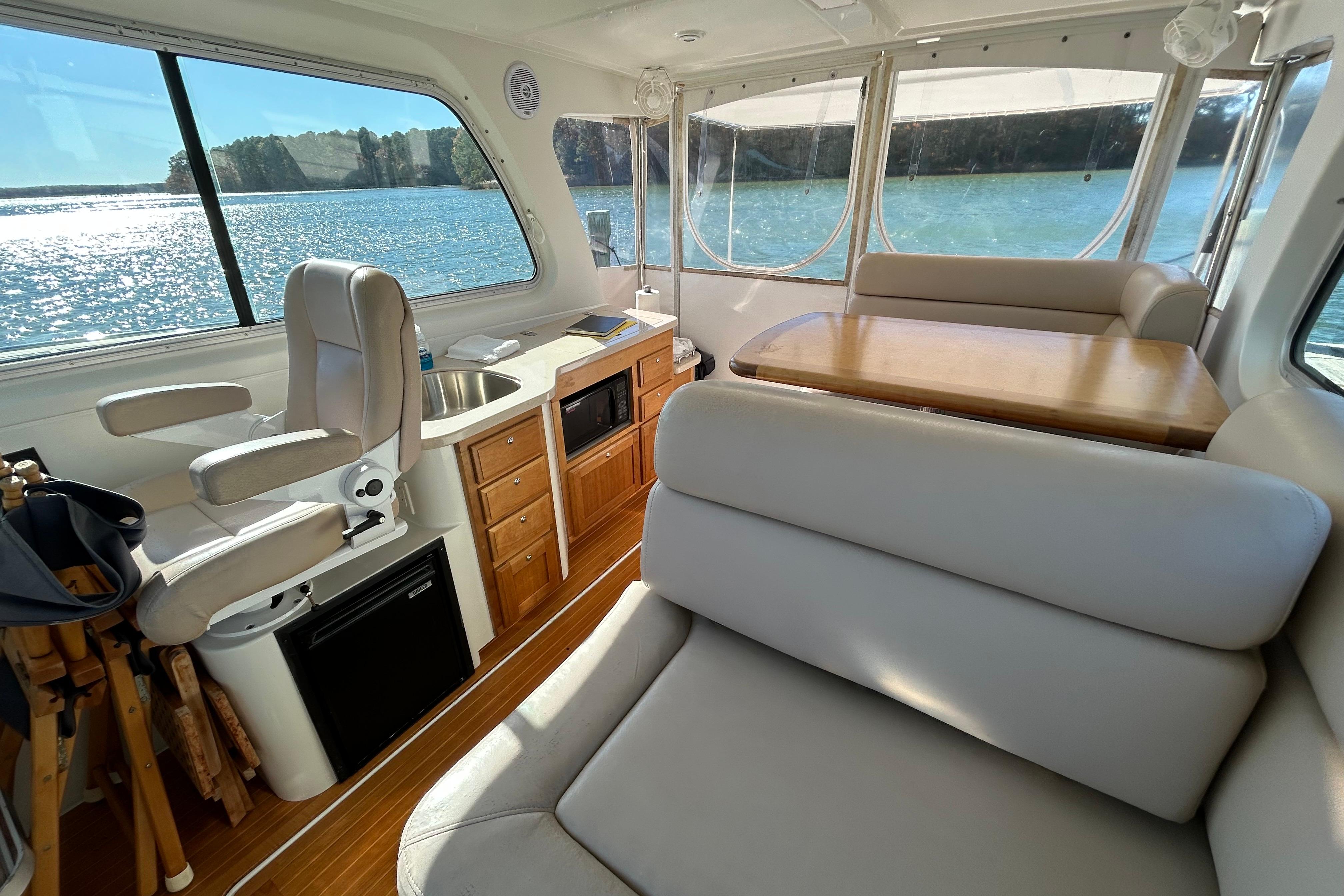 Interior of 2008 Back Cove 33 yacht with seating, table, and kitchenette by the water.
