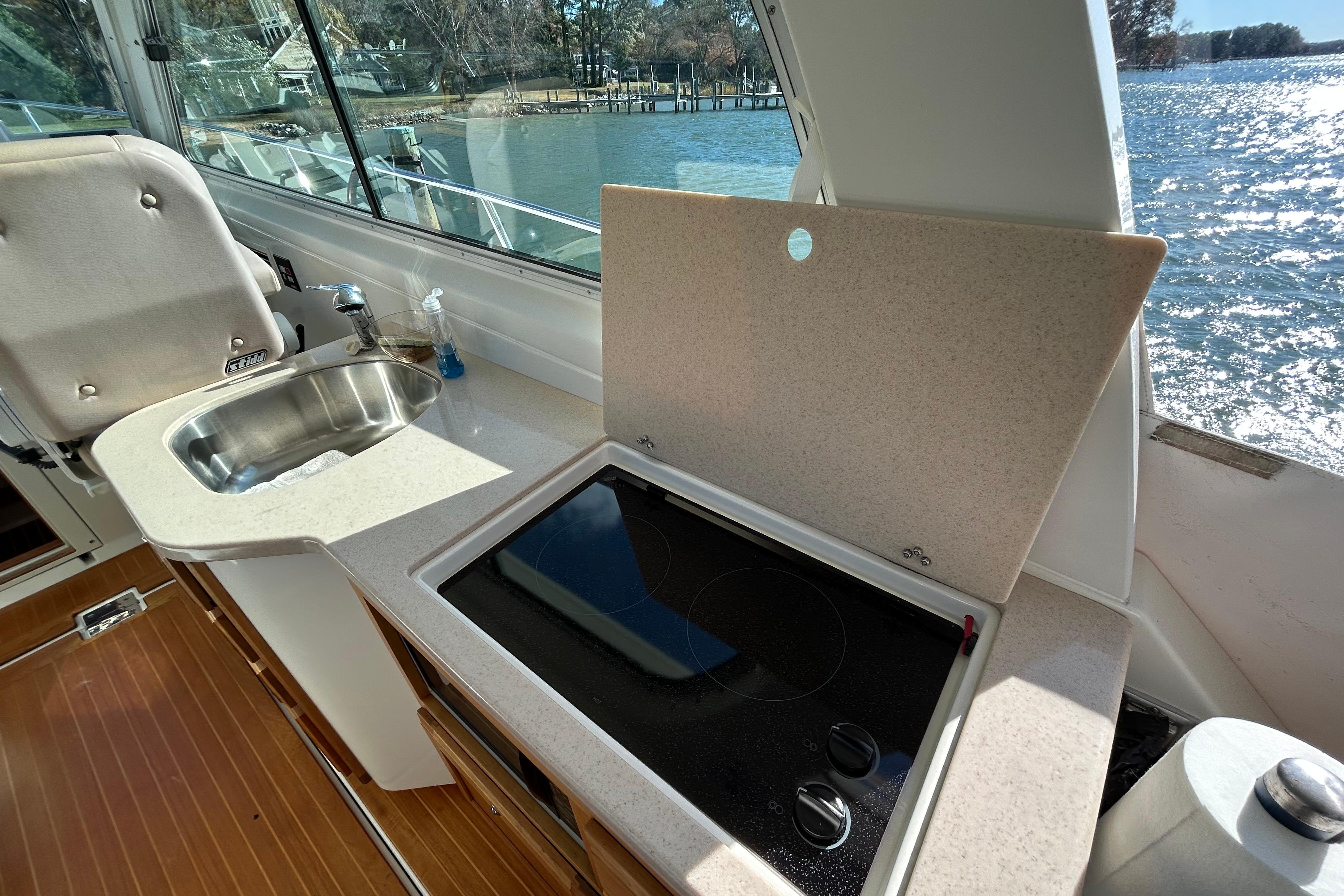2008 Back Cove 33 yacht interior with kitchenette, featuring sink and stove, overlooking water.