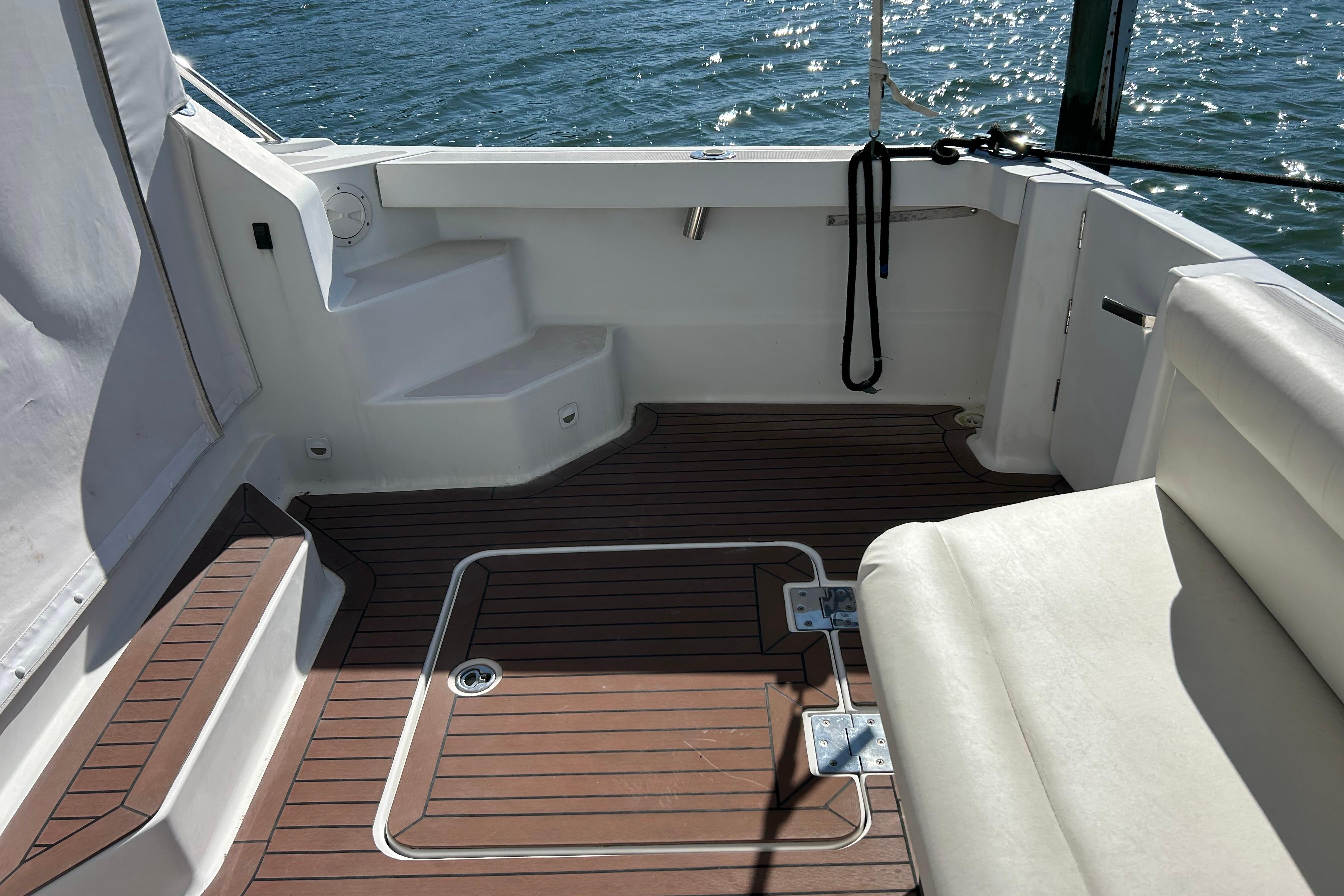 2008 Back Cove 33 boat deck with wooden flooring and white seating, overlooking water.