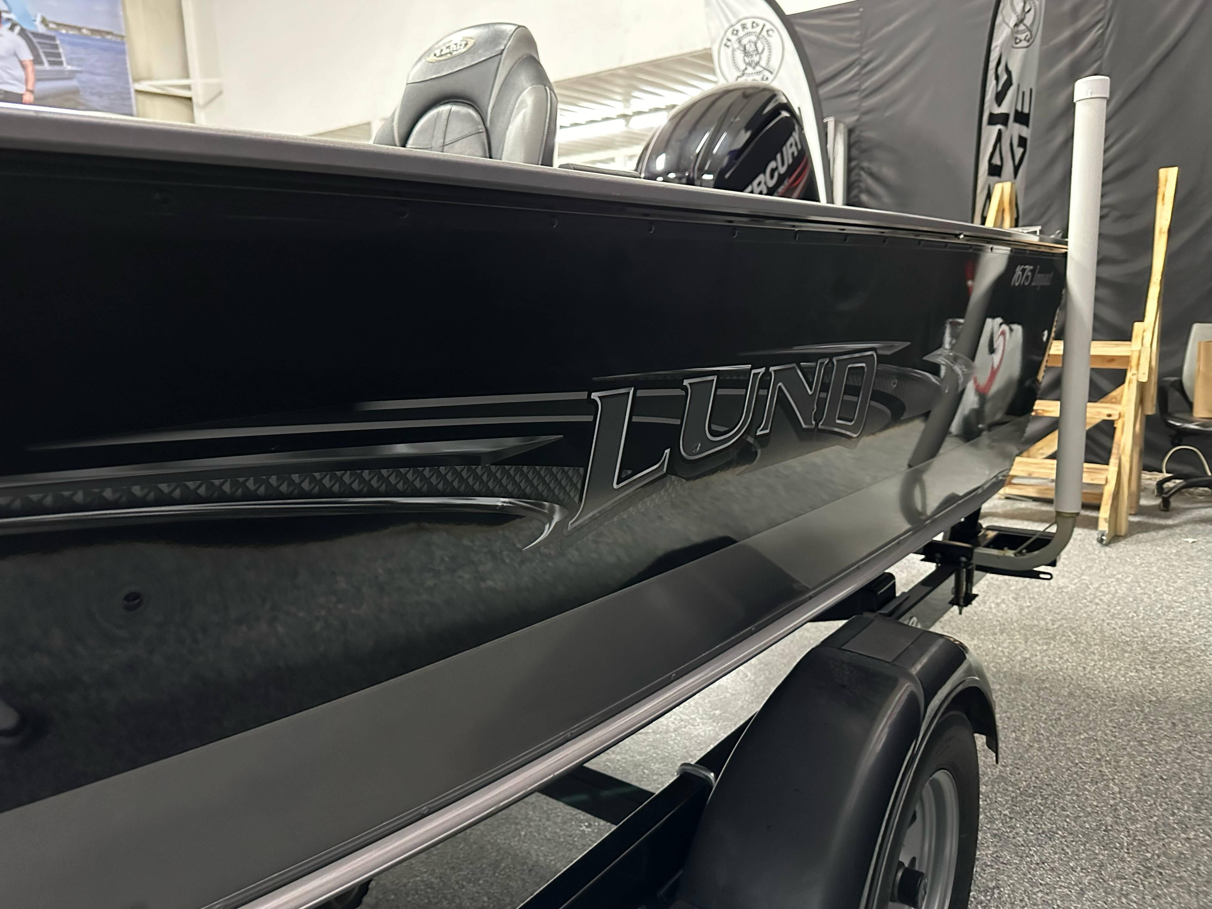 2017 Lund 1675 Impact SS boat, black exterior, displayed indoors on a trailer.
