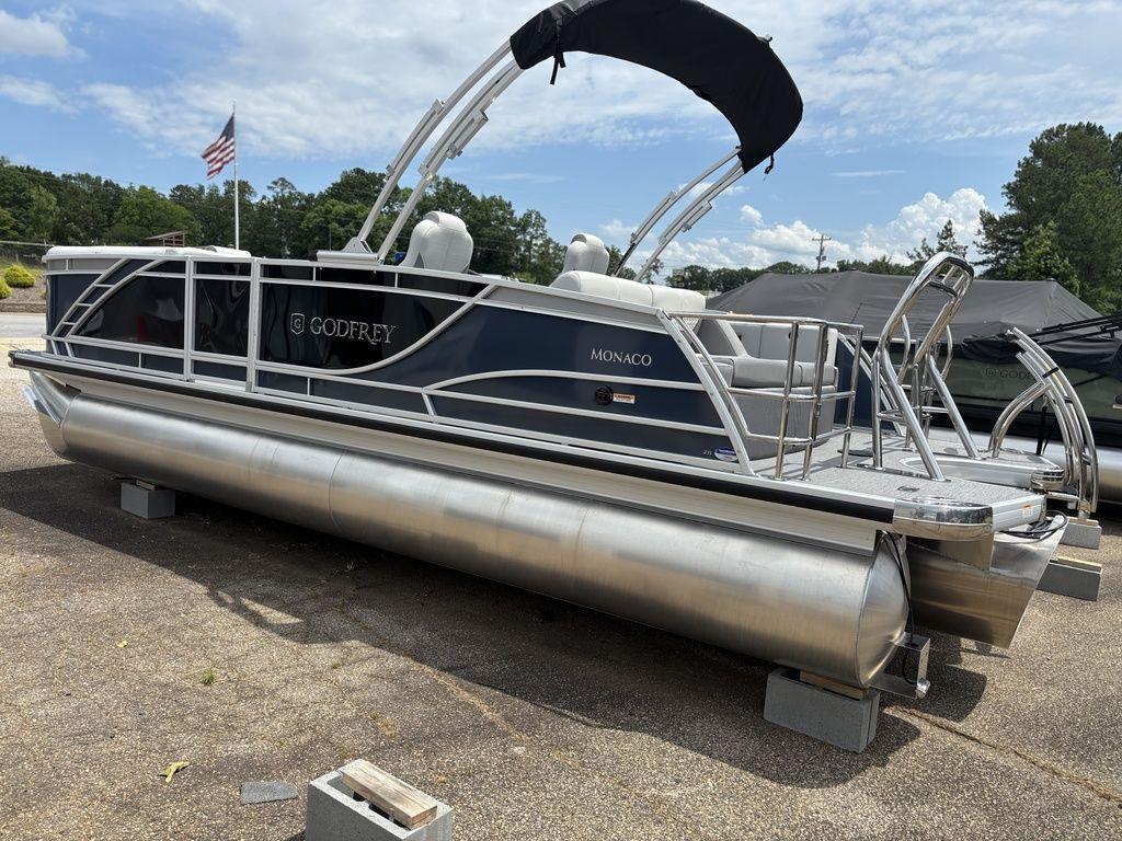 2025 Godfrey Monaco 235 DFL pontoon boat with canopy, parked on land.