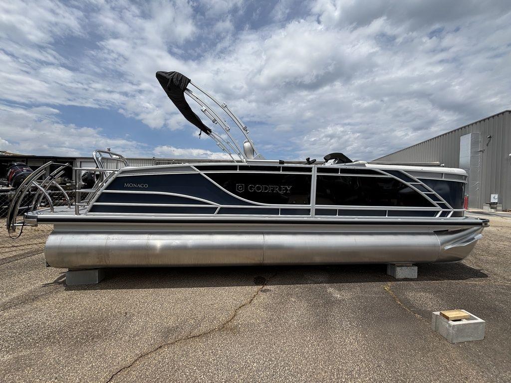 2025 Godfrey Monaco 235 DFL pontoon boat parked outdoors under cloudy sky.