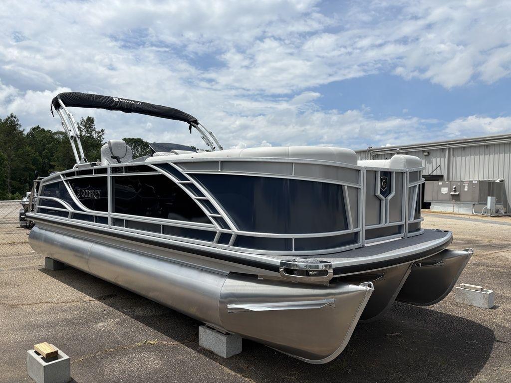 2025 Godfrey Monaco 235 DFL pontoon boat with sleek design, docked outdoors under cloudy sky.