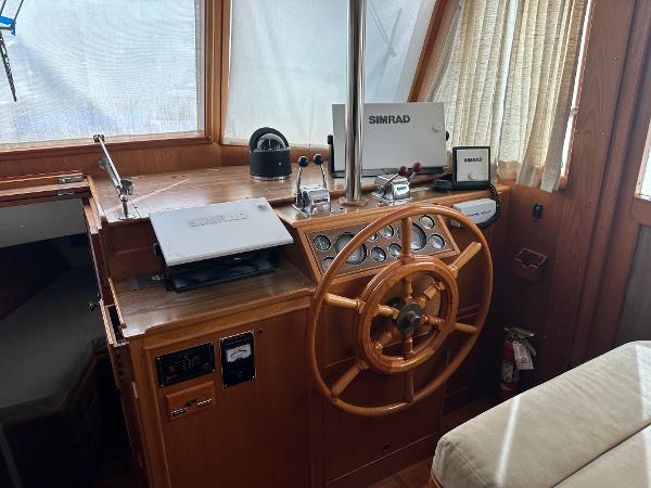 1982 Grand Banks Classic helm with wooden wheel and Simrad navigation equipment.