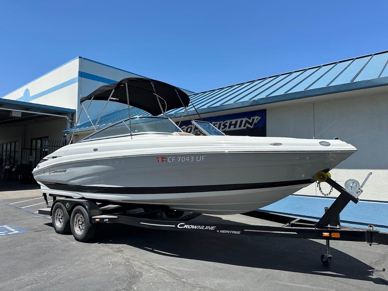2019 Crownline 235 SS boat on trailer, parked outside a building under clear blue sky.