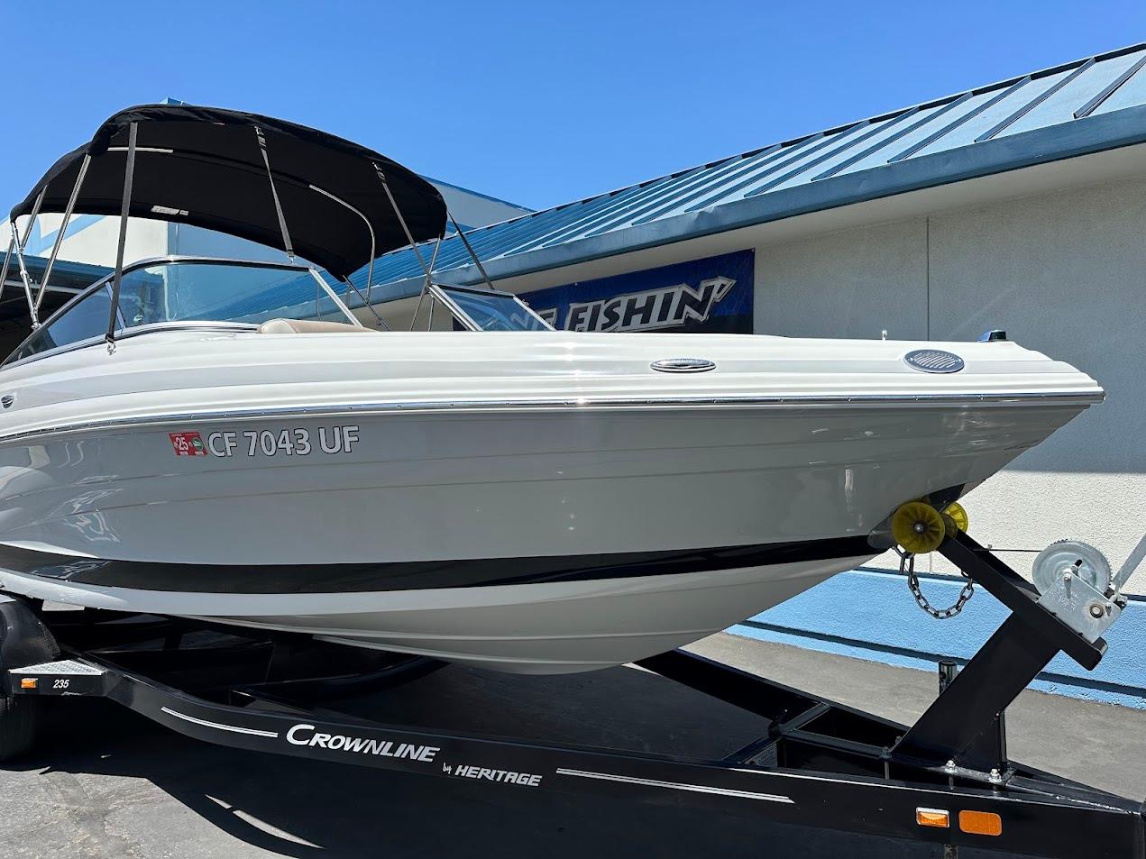 2019 Crownline 235 SS boat on trailer, black canopy, parked outdoors.