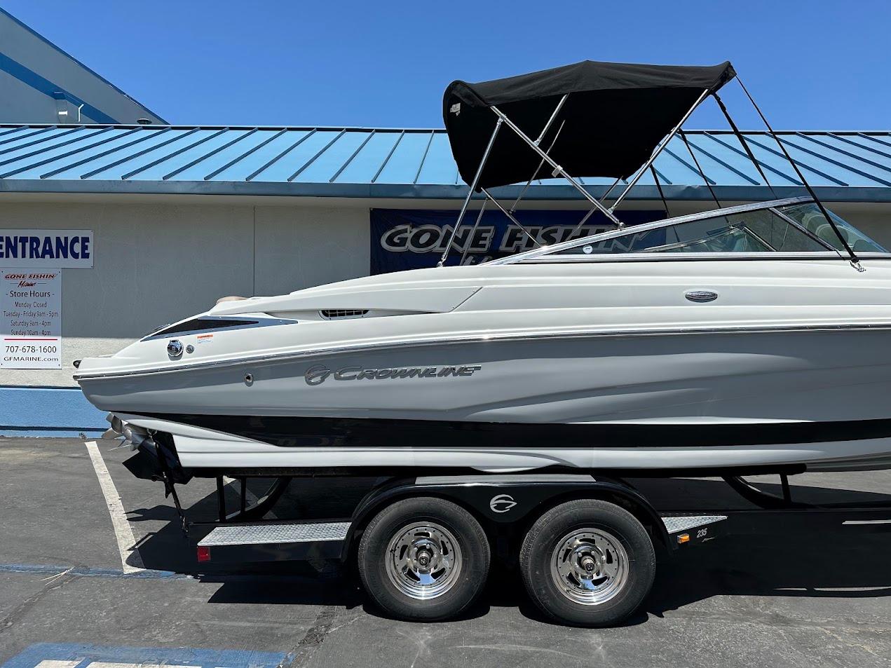 2019 Crownline 235 SS boat on trailer, parked outside a building with blue roof.