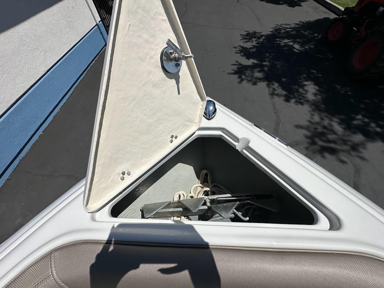 Open storage compartment on 2019 Crownline 235 SS boat, containing anchor and rope.