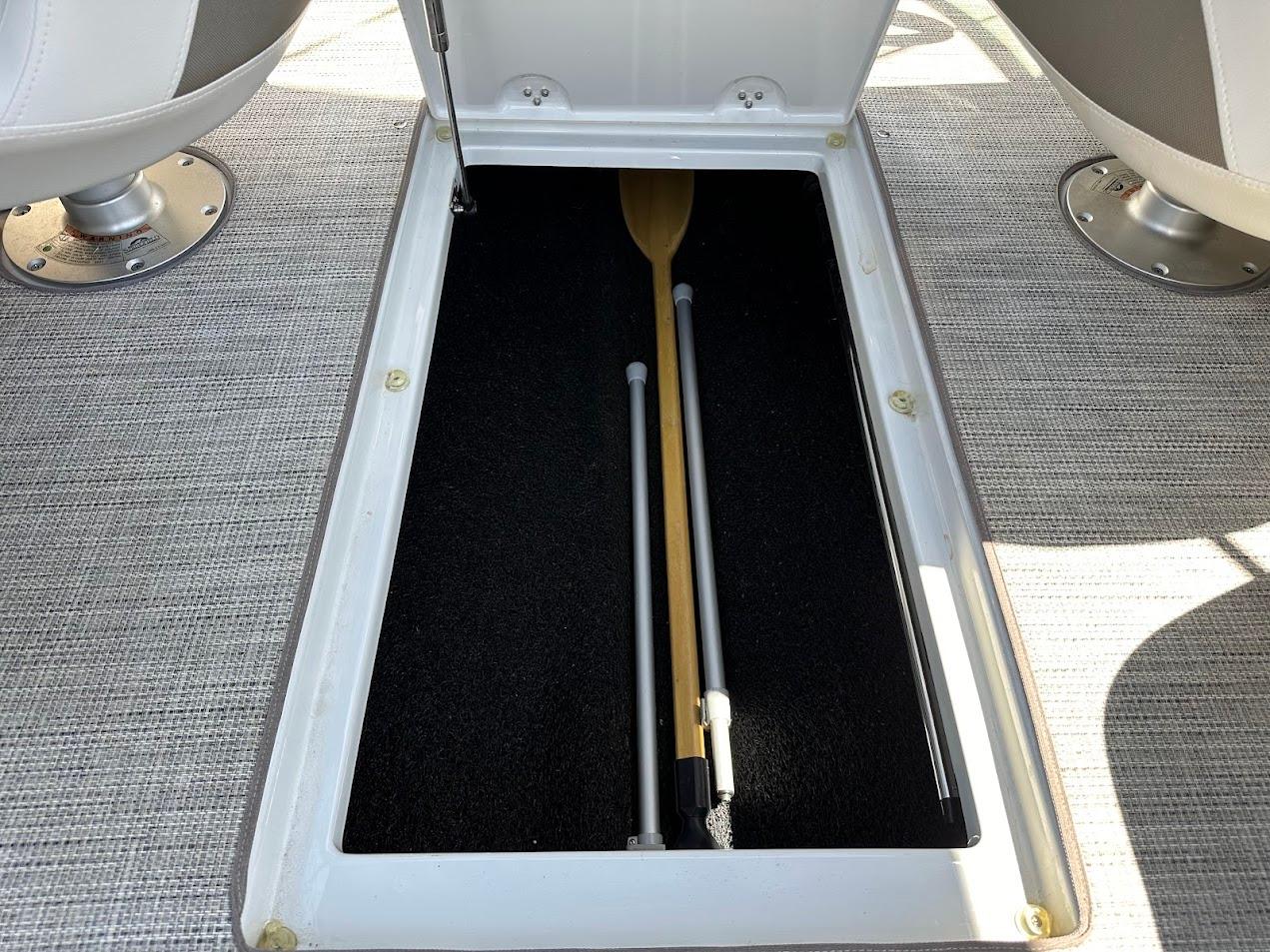 Storage compartment in 2019 Crownline 235 SS boat with paddle and poles.
