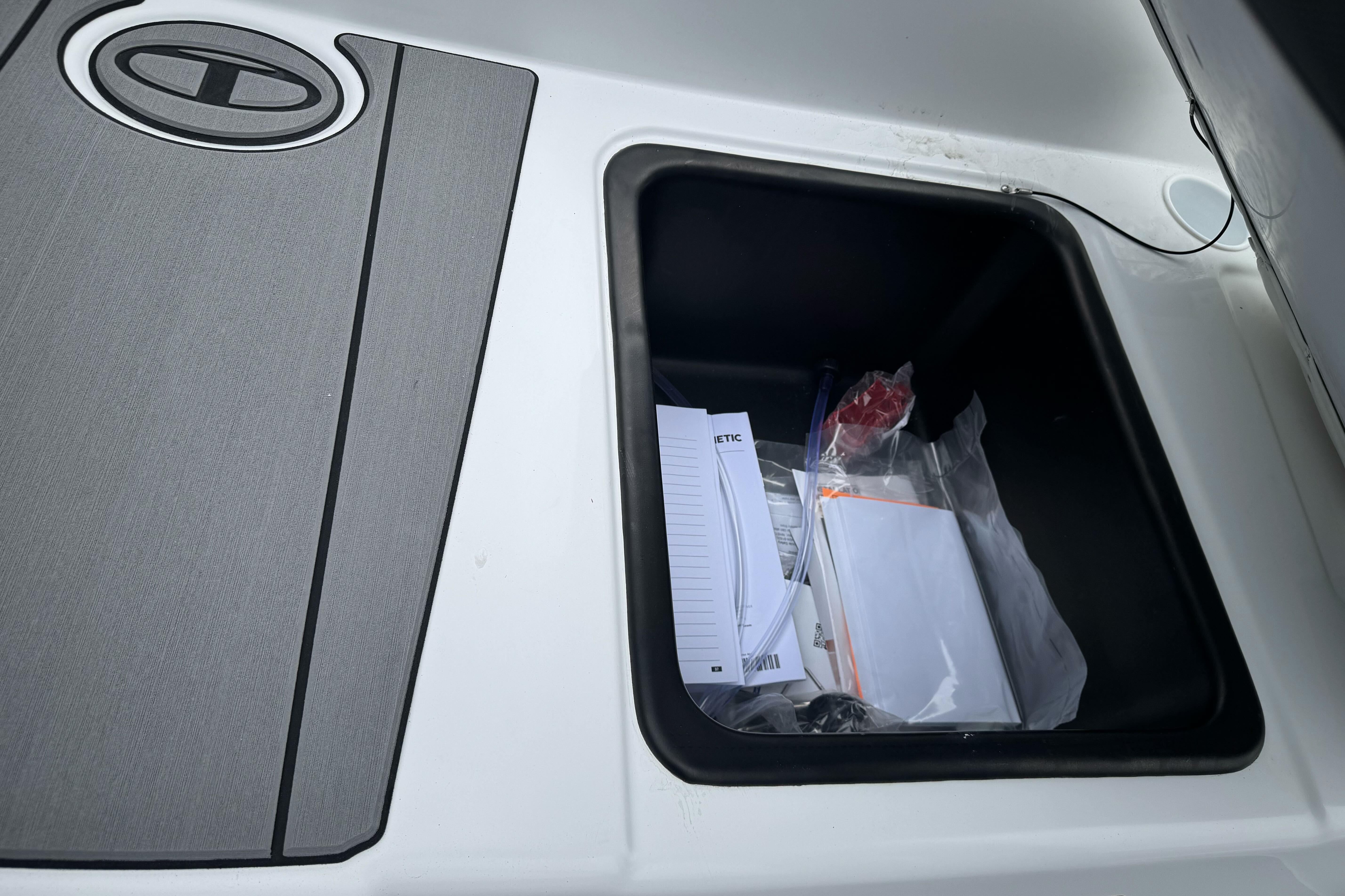 Storage compartment in 2026 Tahoe T18 boat with documents and accessories.