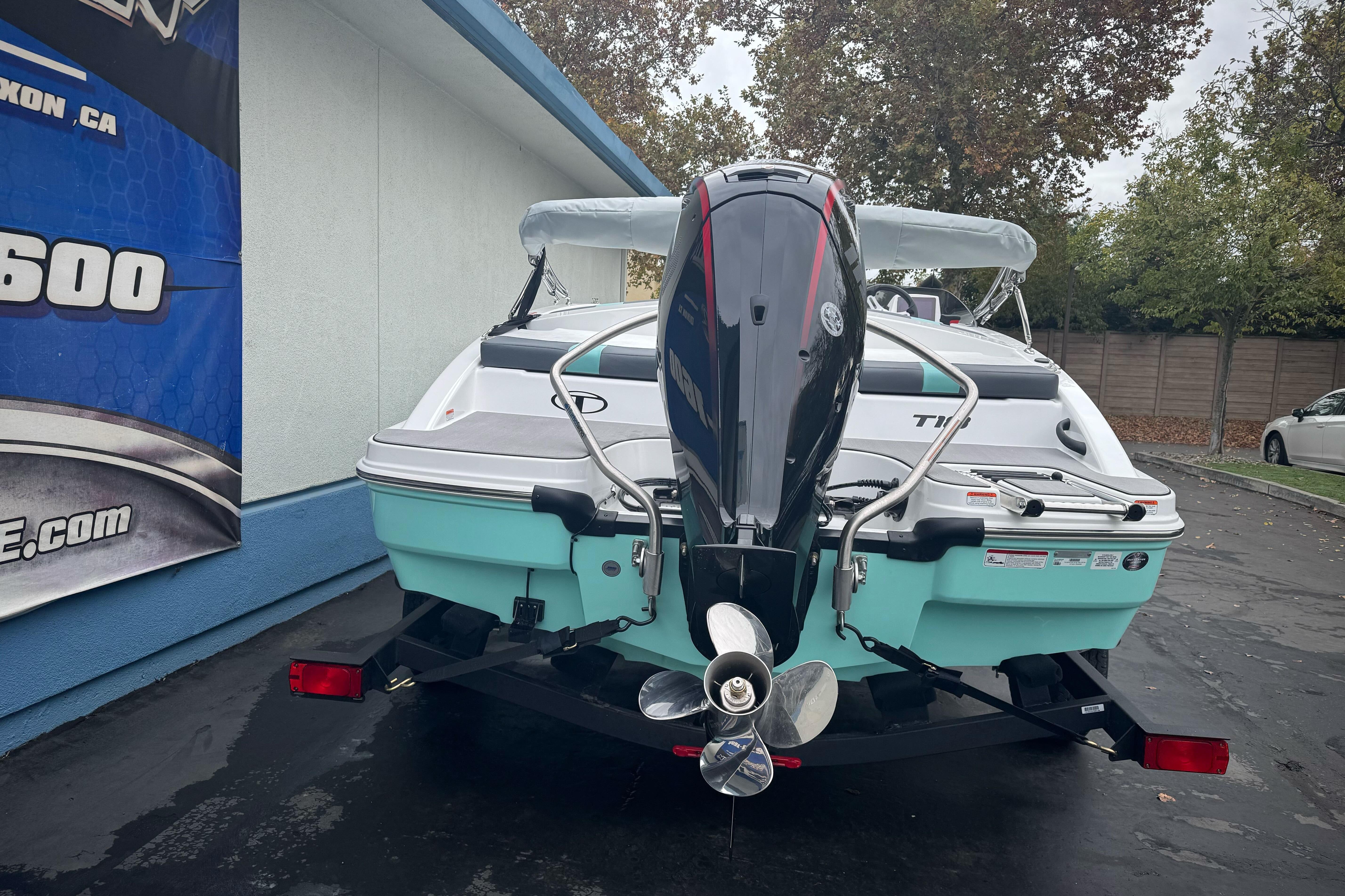 2026 Tahoe T18 boat with outboard motor, parked outdoors near a building.