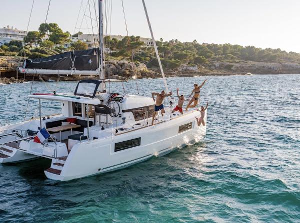 People enjoying on a 2020 Lagoon 40 catamaran in scenic coastal waters.