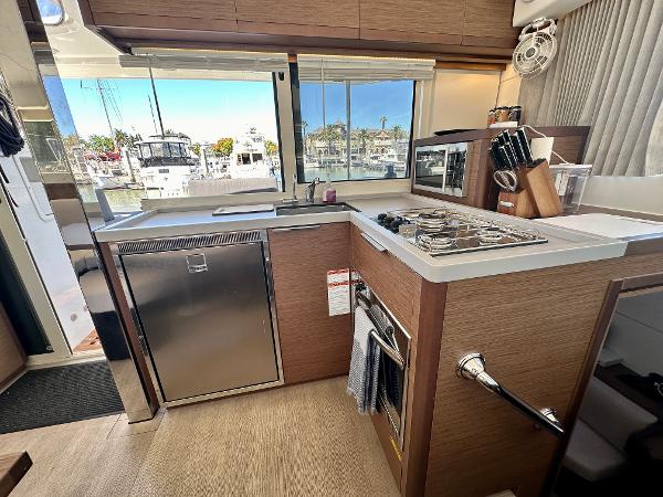 Modern kitchen interior of 2020 Lagoon 40 catamaran with stainless steel appliances and wooden cabinetry.