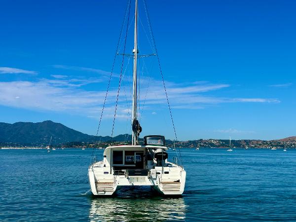 2020 Lagoon 40 catamaran on calm water with scenic mountain backdrop.