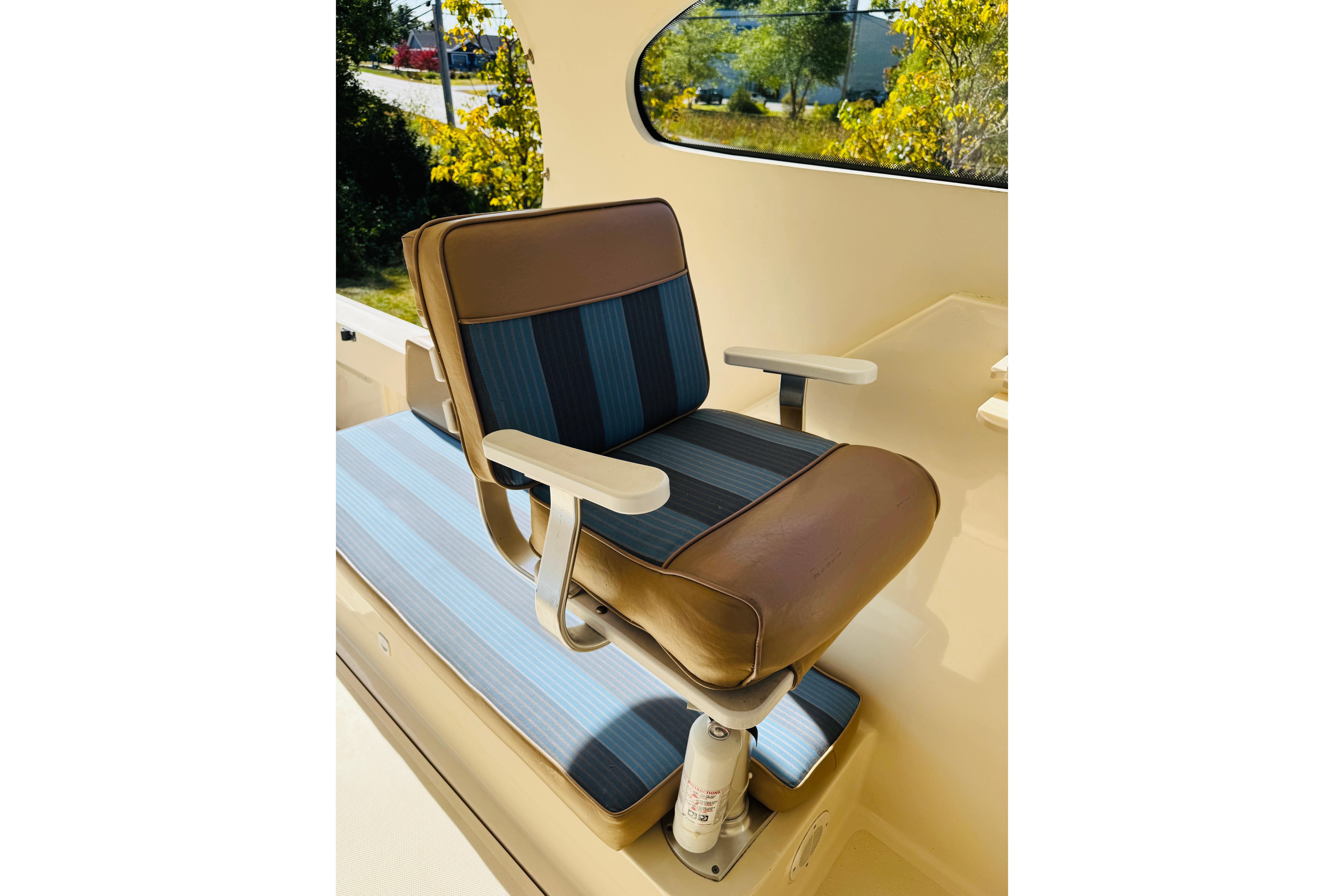 Captainu0027s chair on 2006 Mainship Pilot 30 Sedan boat, featuring blue and brown upholstery.