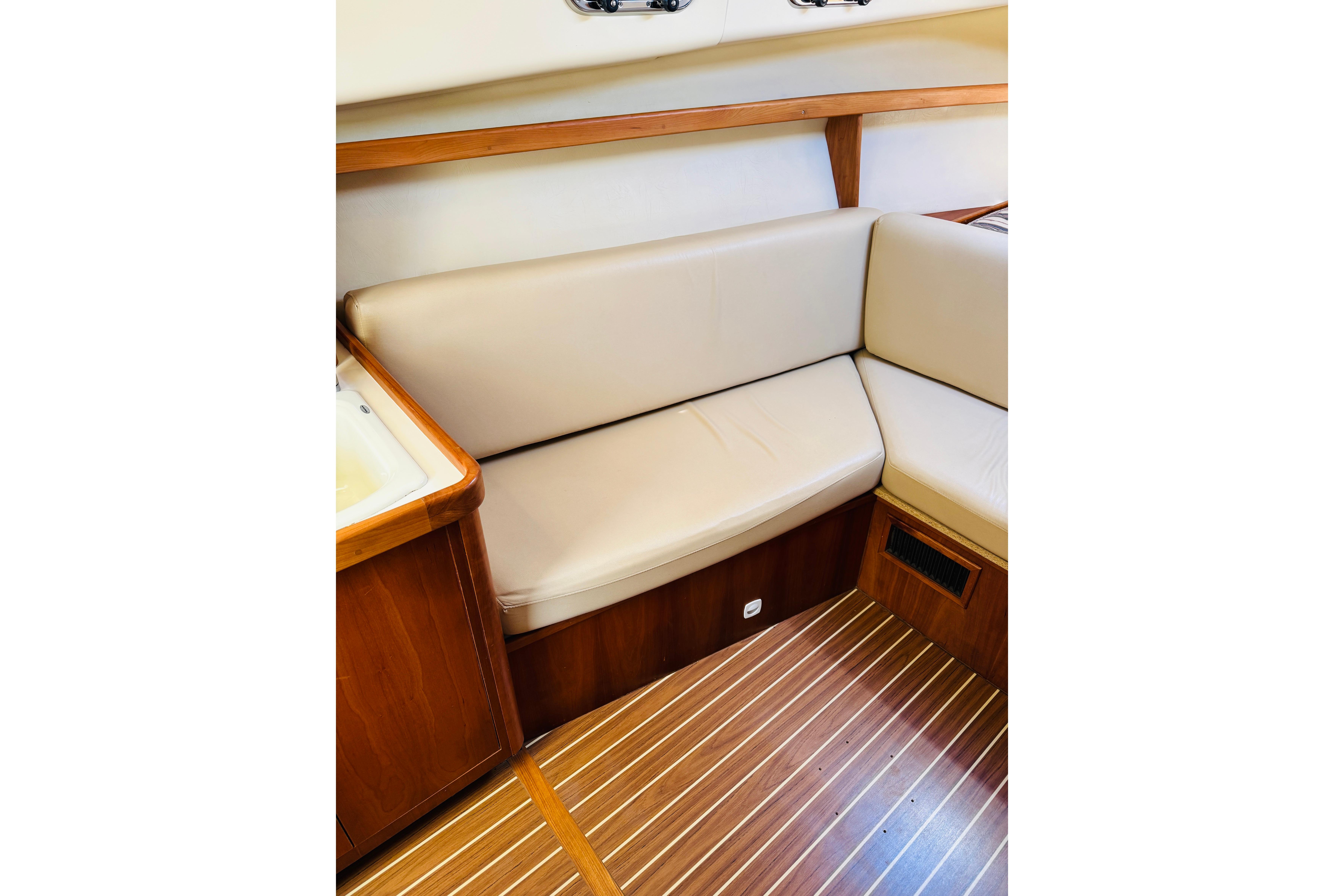 2006 Mainship Pilot 30 Sedan interior with beige seating and wooden flooring.