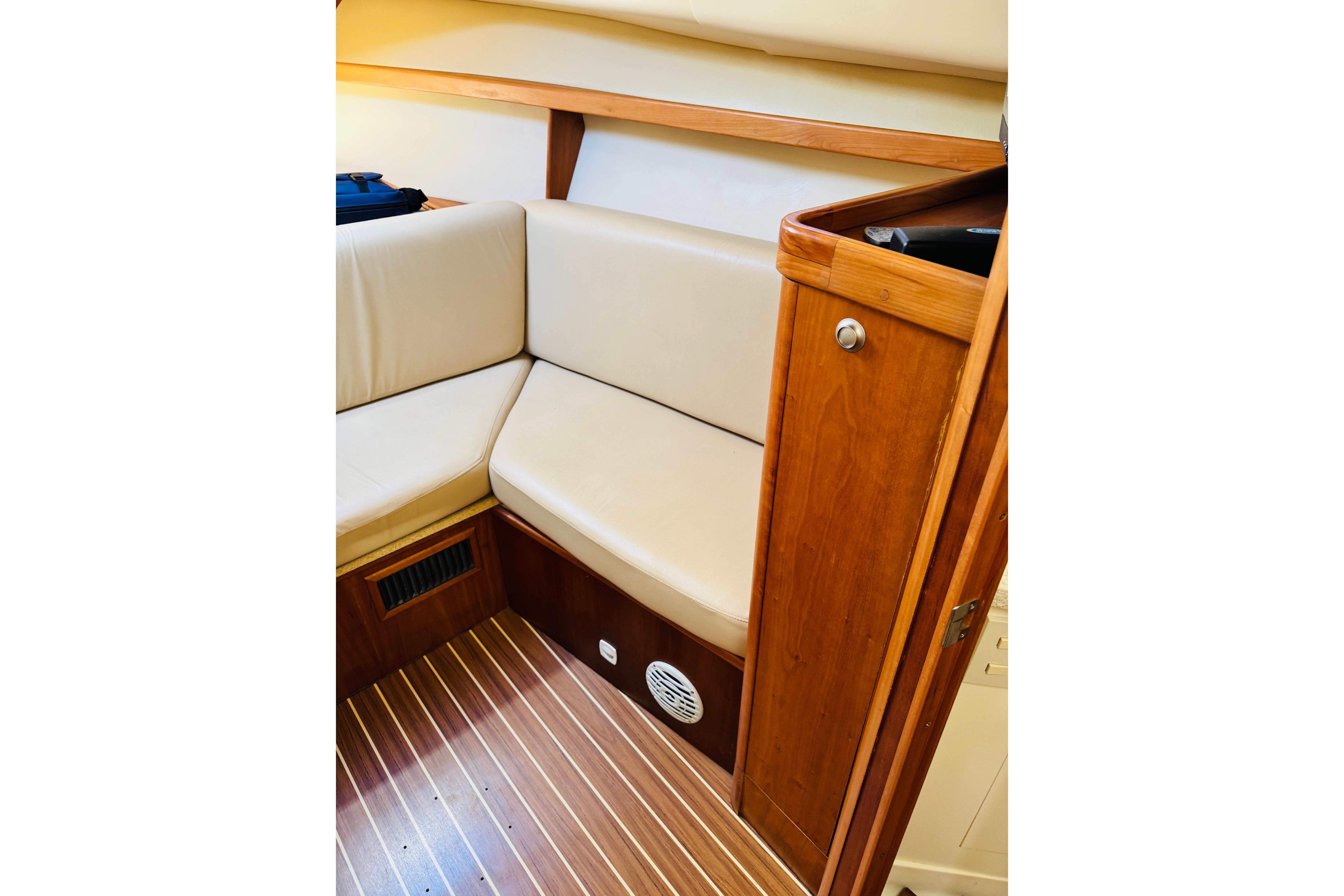 2006 Mainship Pilot 30 Sedan interior with beige seating and wooden cabinetry.