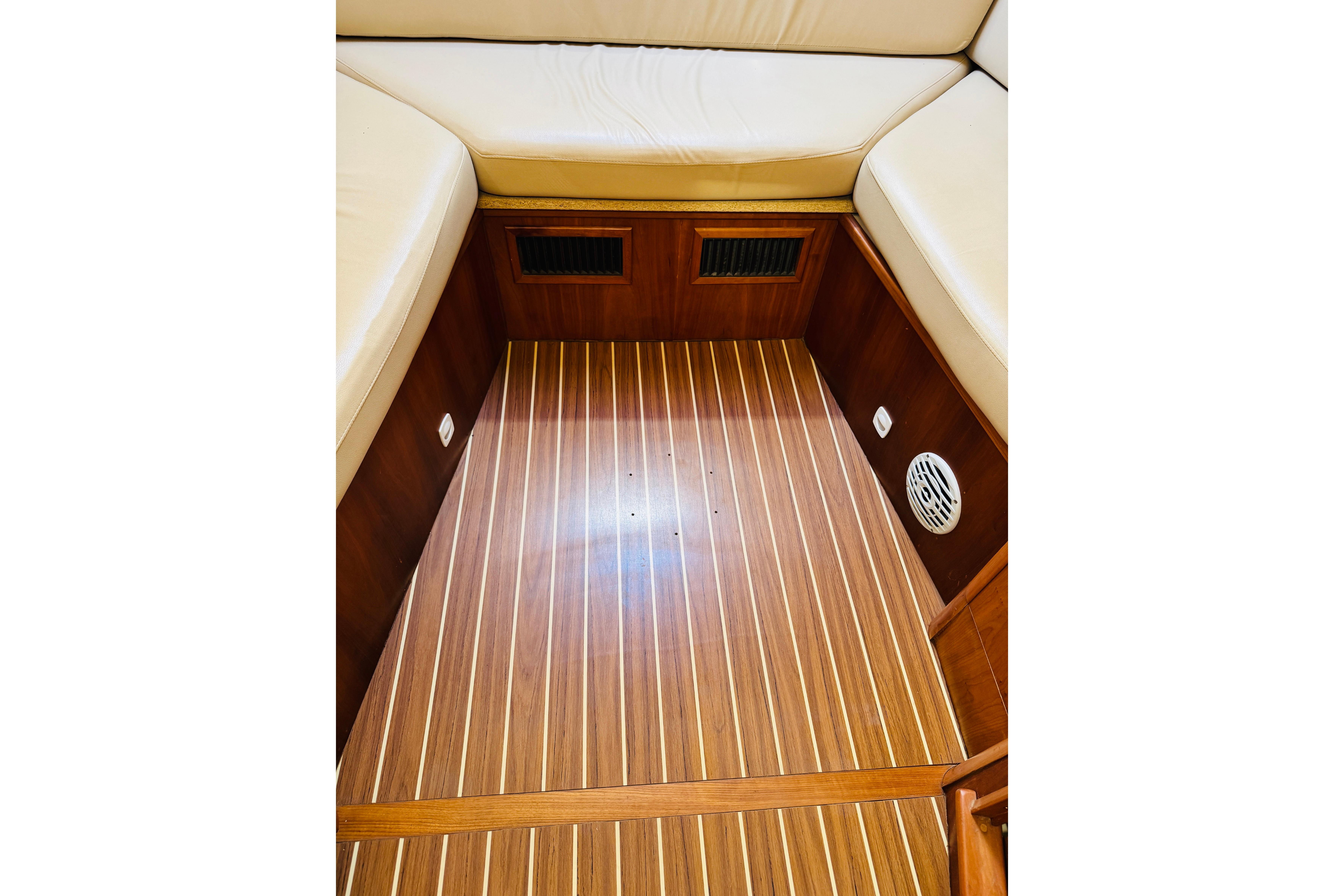 2006 Mainship Pilot 30 Sedan interior with wood flooring and cushioned seating.