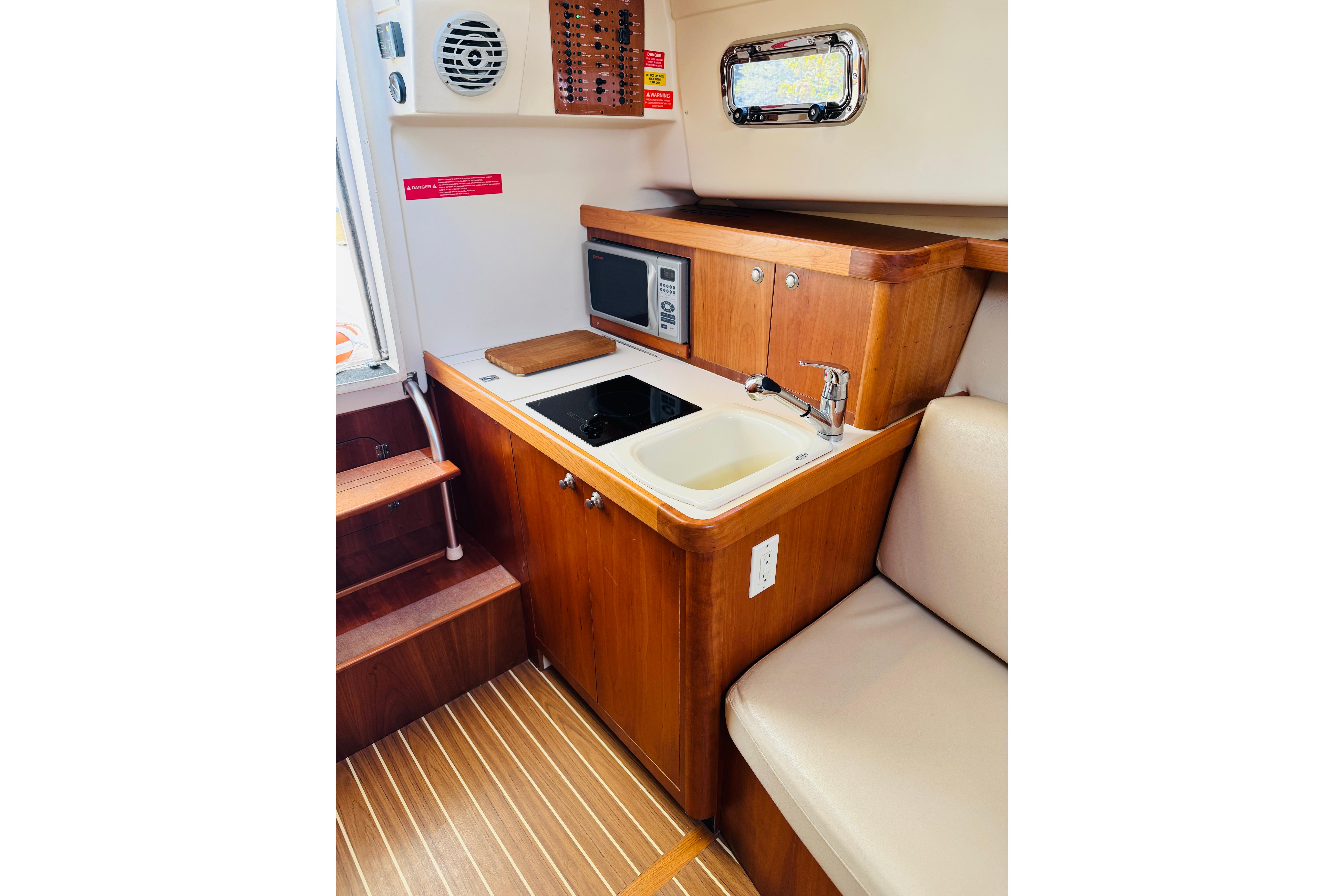 2006 Mainship Pilot 30 Sedan interior with kitchenette, featuring sink, stove, and microwave.