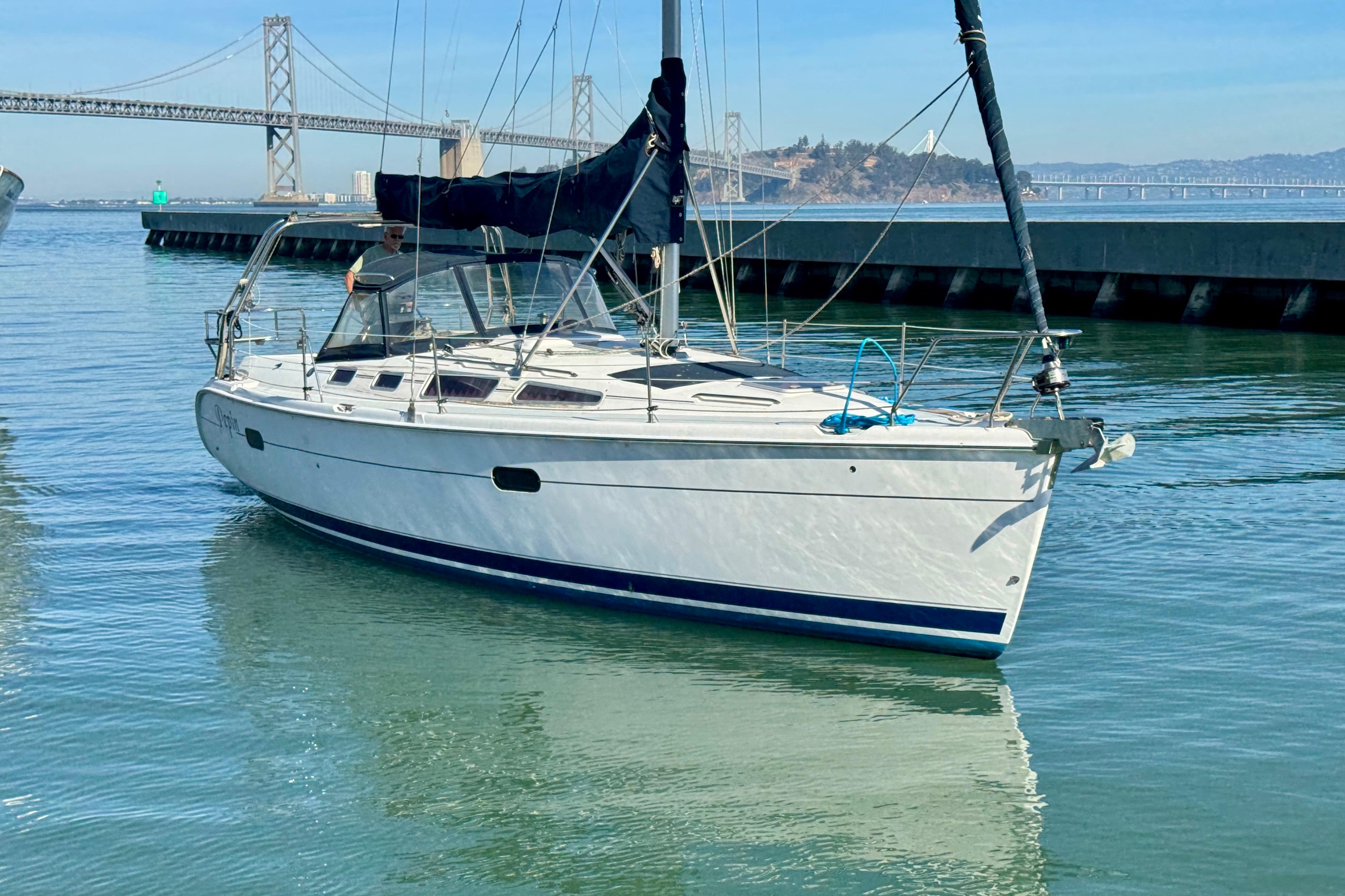 2003 Hunter 36 sailboat on calm water near a bridge.