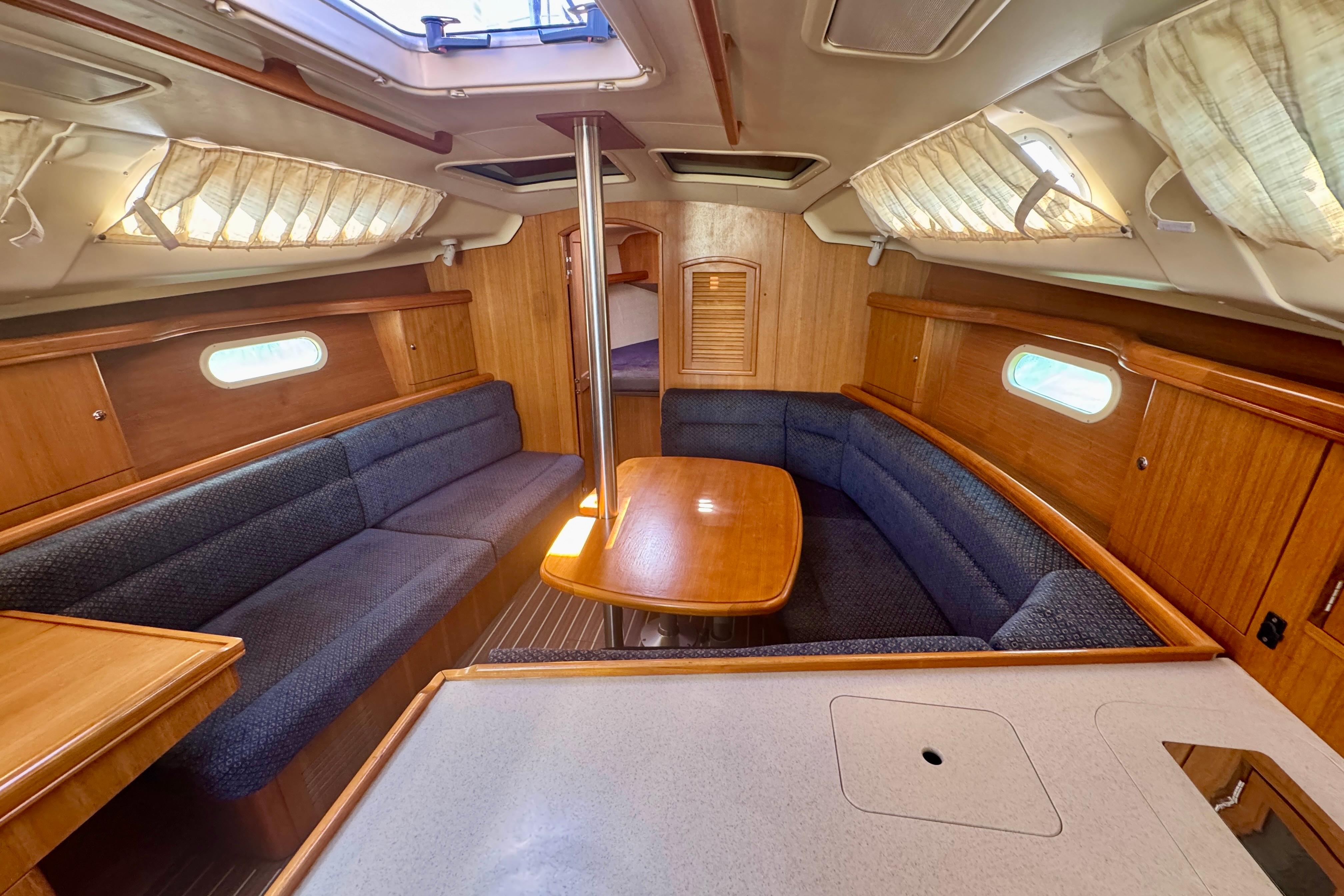 Interior of a 2003 Hunter 36 sailboat with wood finish and cozy seating area.
