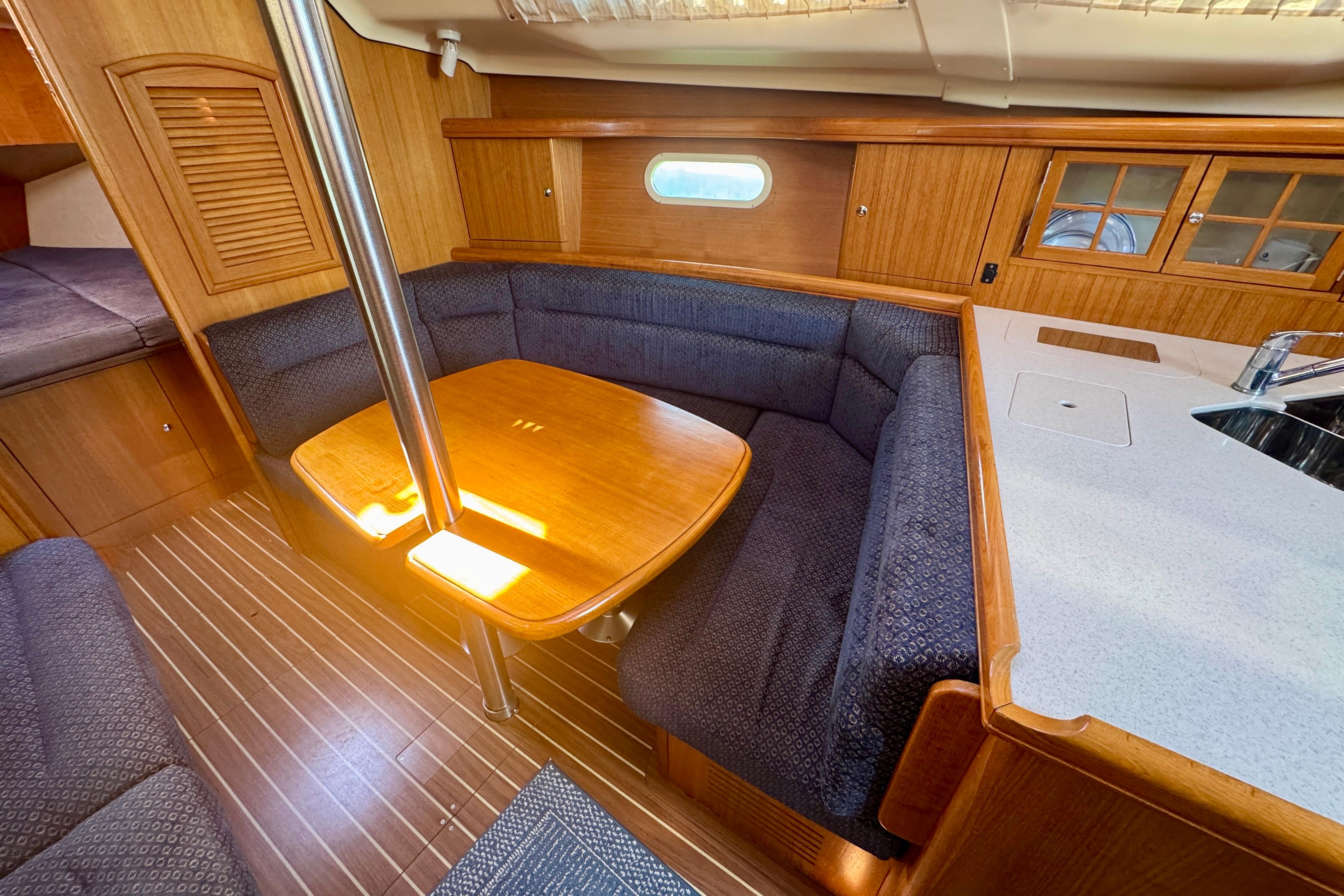 Interior of 2003 Hunter 36 sailboat with wooden dining area and seating.
