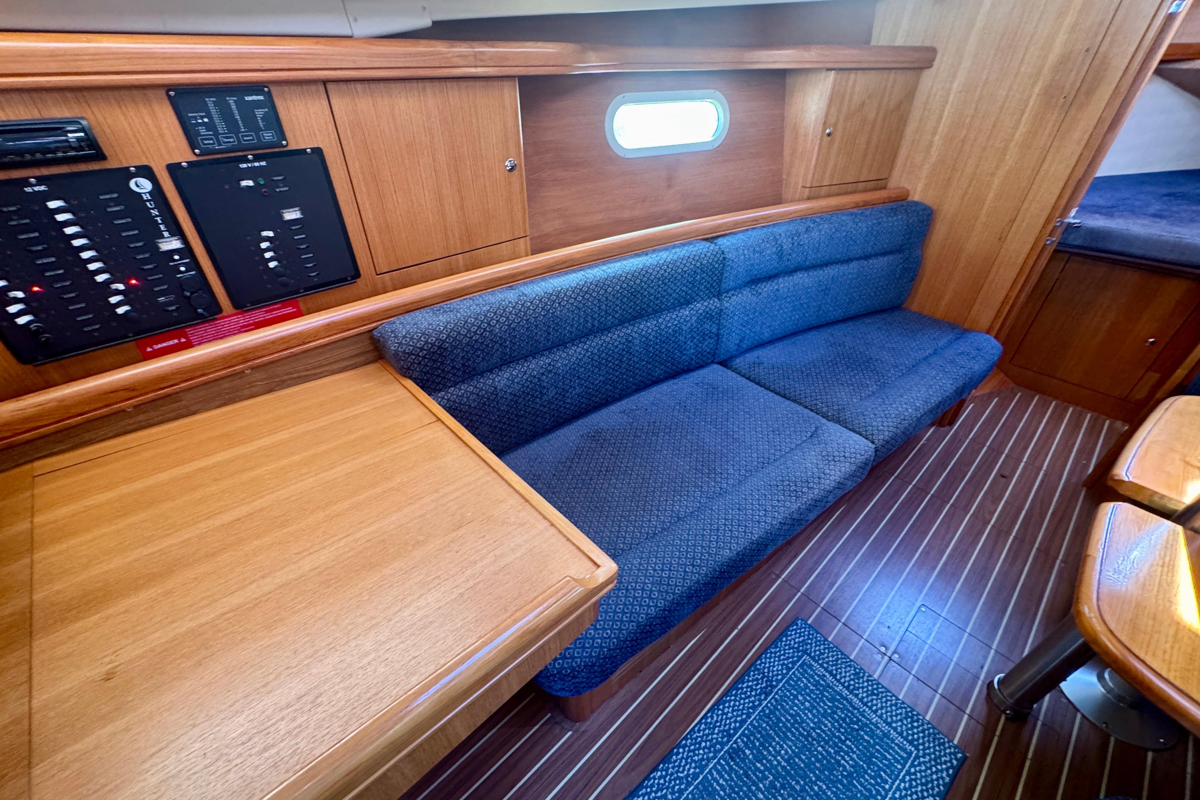 Interior of 2003 Hunter 36 sailboat with blue sofa and wooden cabinetry.
